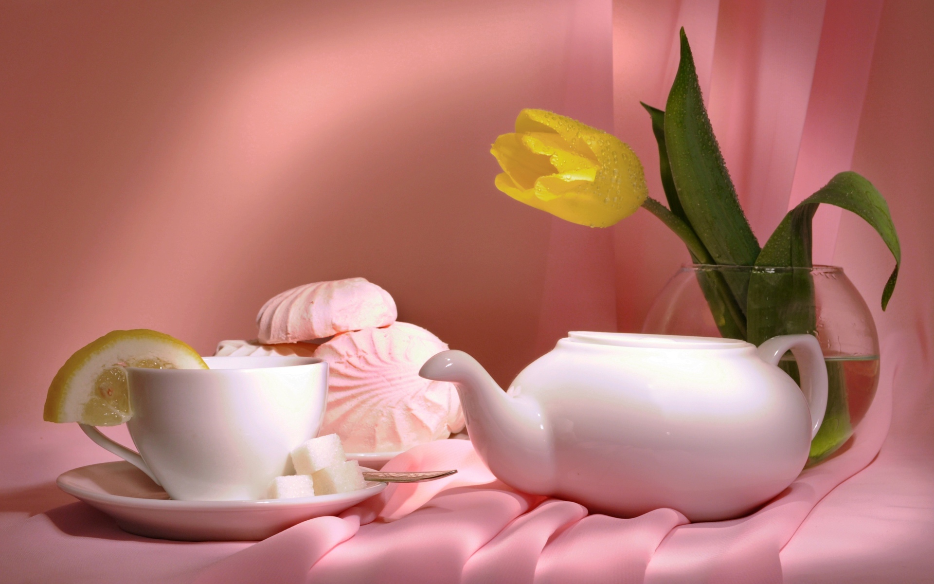 Чайник на столе с чашкой, зефиром и желтым тюльпаном