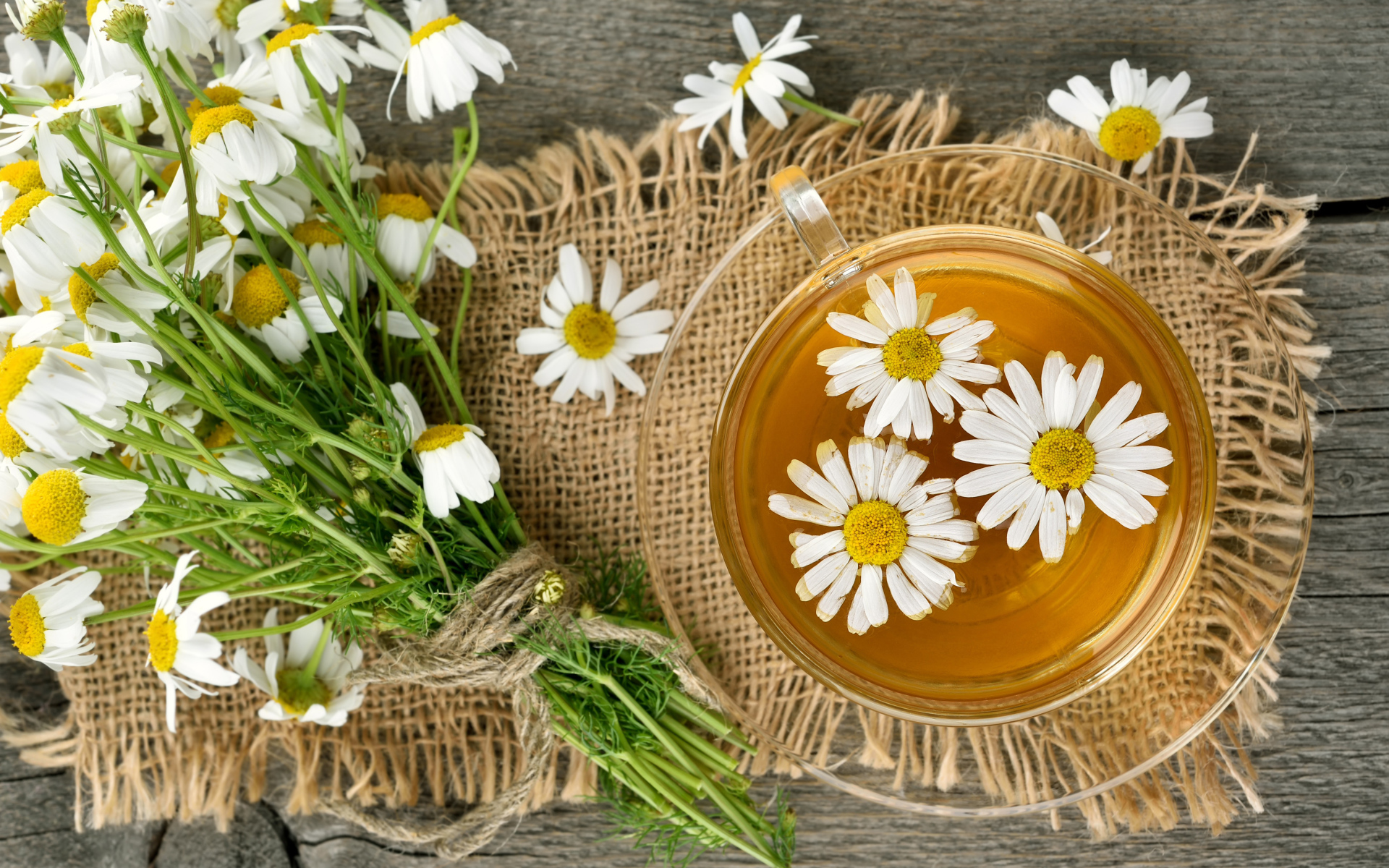 Чай в стеклянной чашке на столе с ромашкой