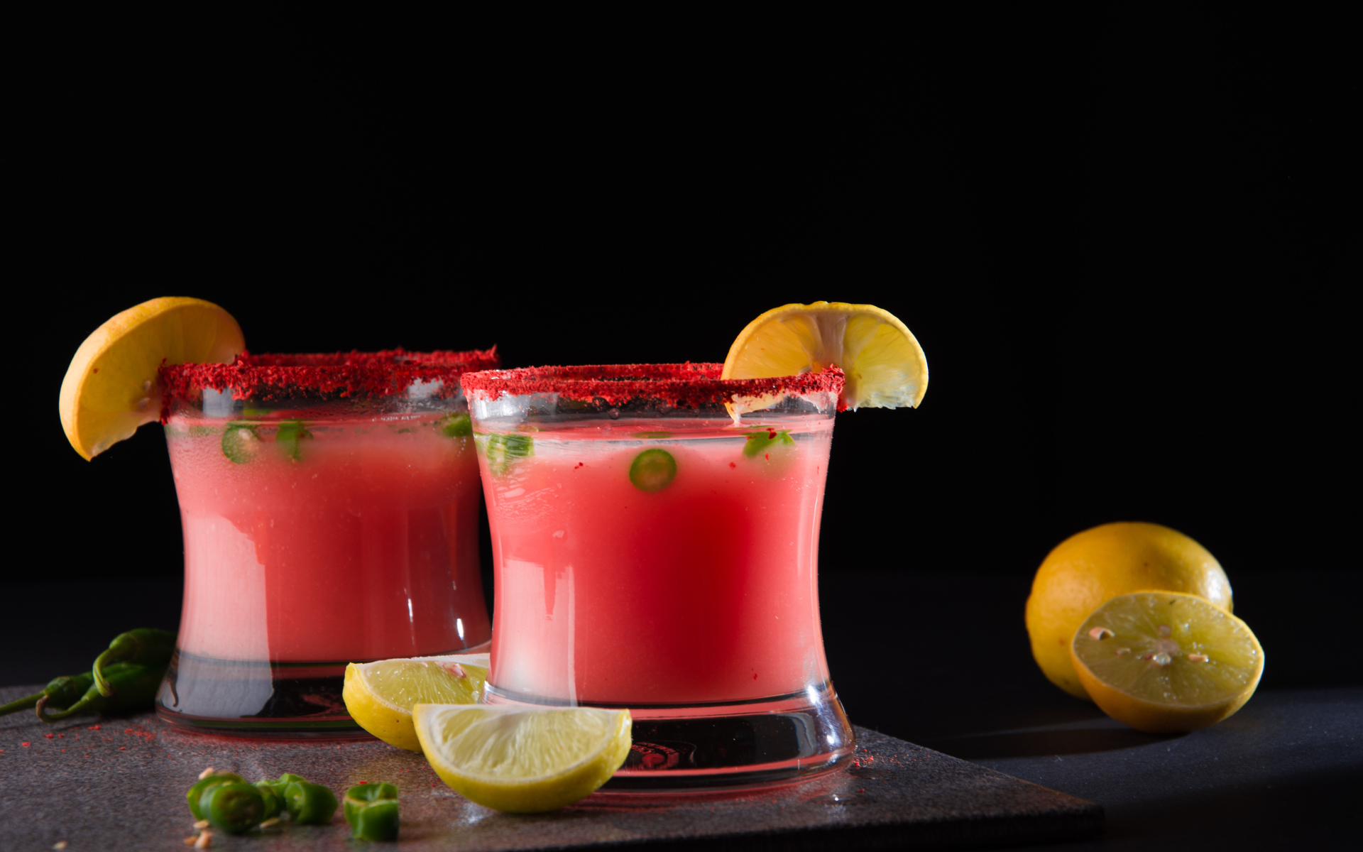 Два стакана с коктейлем на черном фоне с лимоном