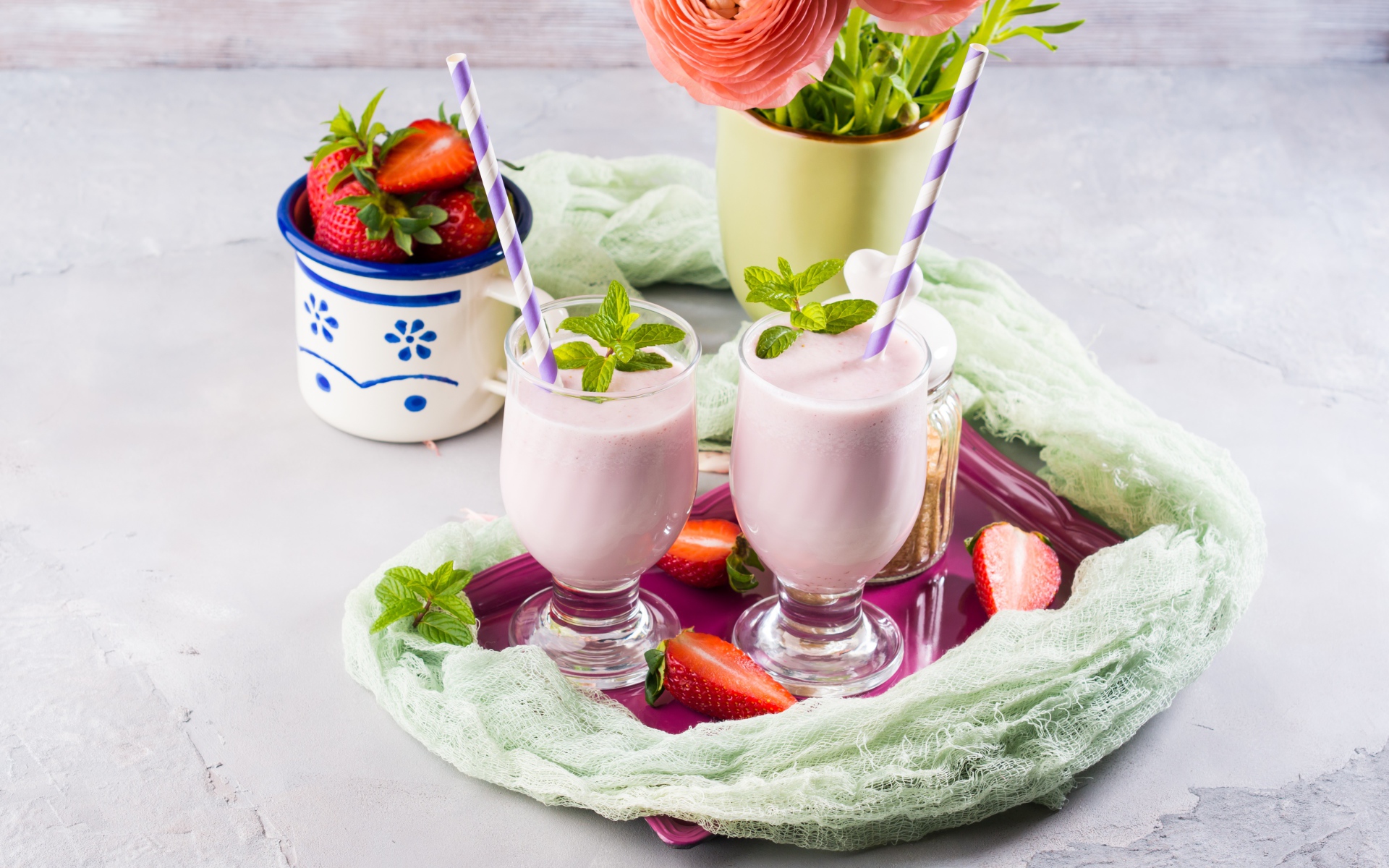 Два стакана с коктейлем на столе с букетом и клубникой