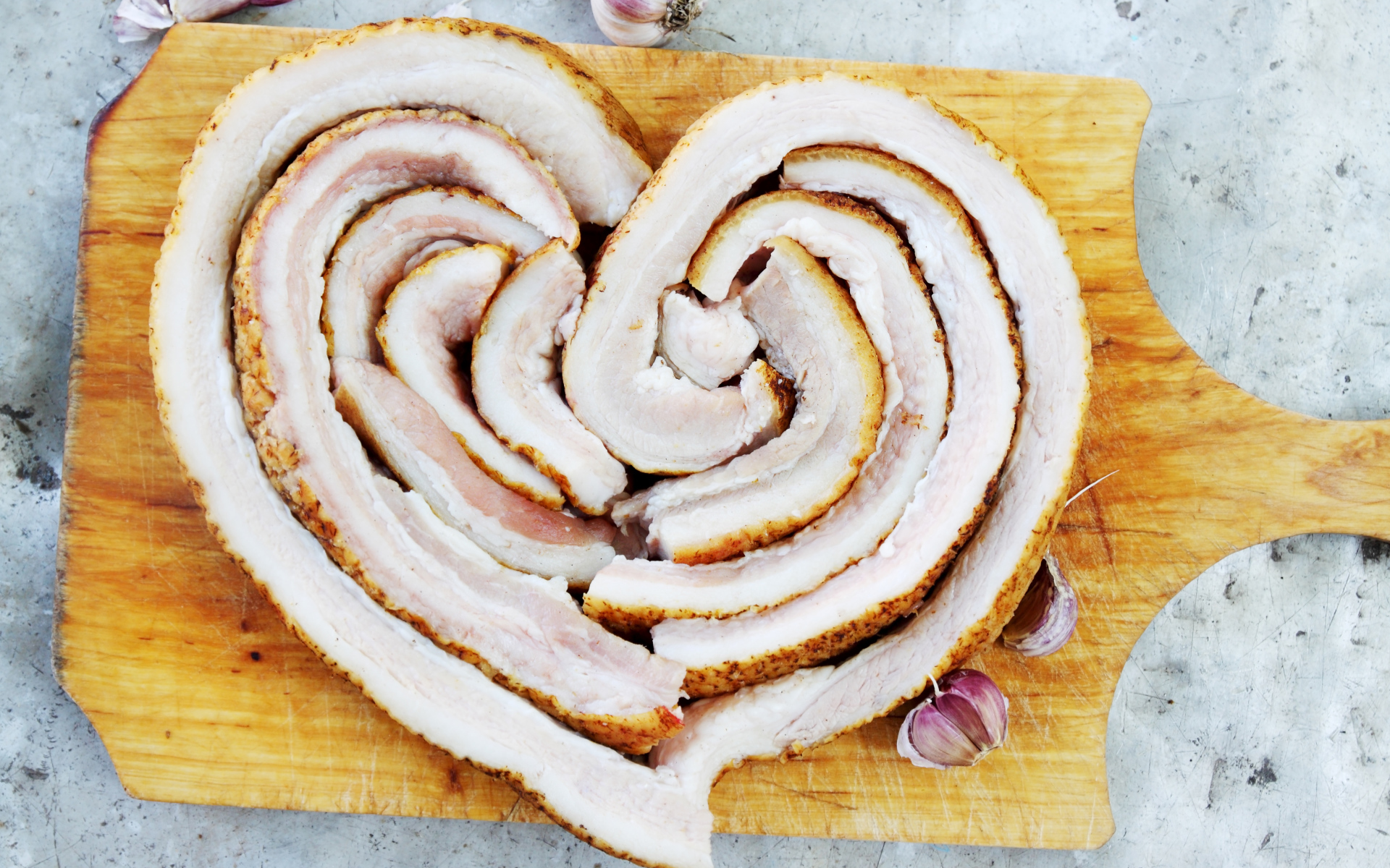 Heart of fresh bacon on a board with garlic