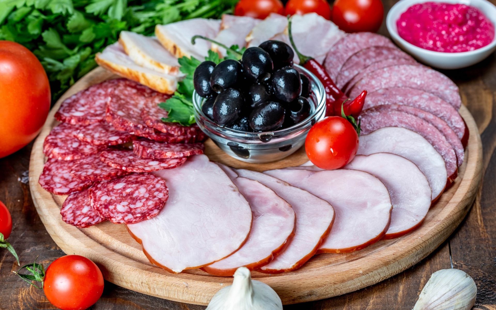 Колбасные продукты на доске с оливками