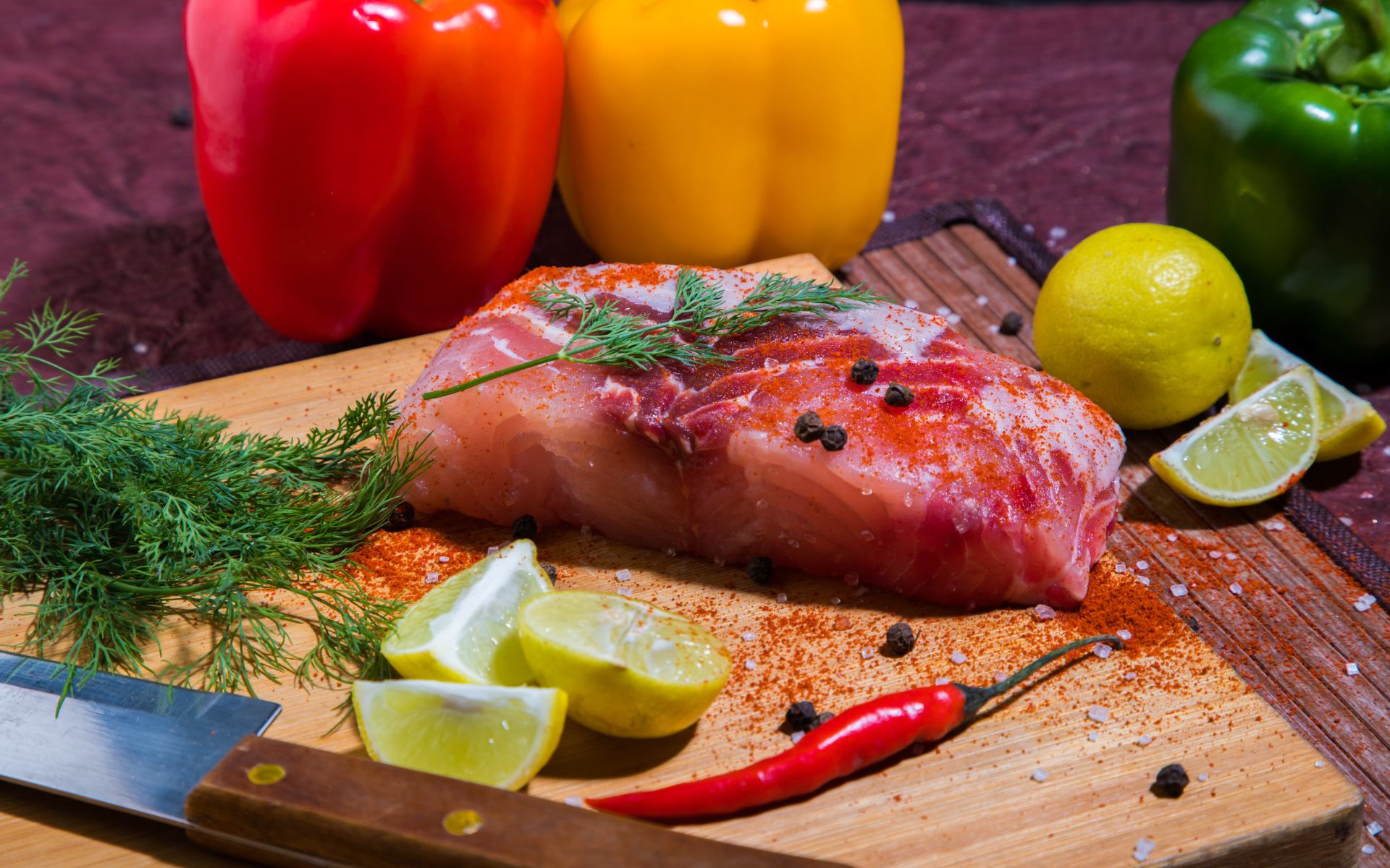 Кусок сырой рыбы на разделочной доске со специями, лимоном и болгарским перцем