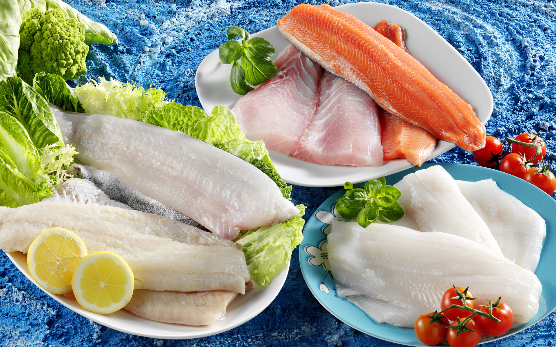 Филе рыбы на тарелках с помидорами и листьями салата