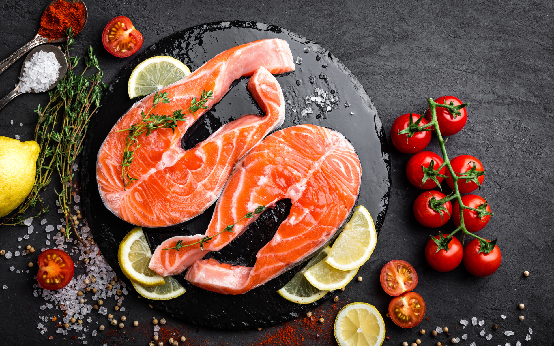 Два куска красной рыбы с овощами на черном фоне