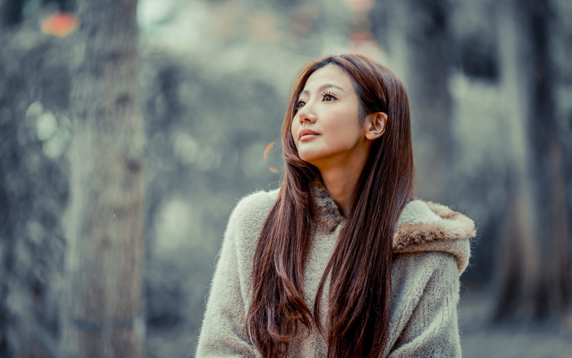 Длинноволосая девушка азиатка смотрит в сторону