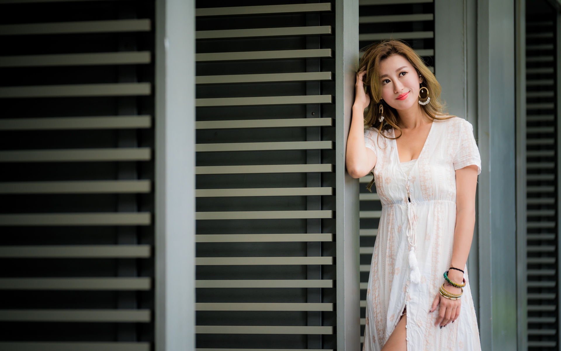 Красивая девушка азиатка в платье стоит у дверей