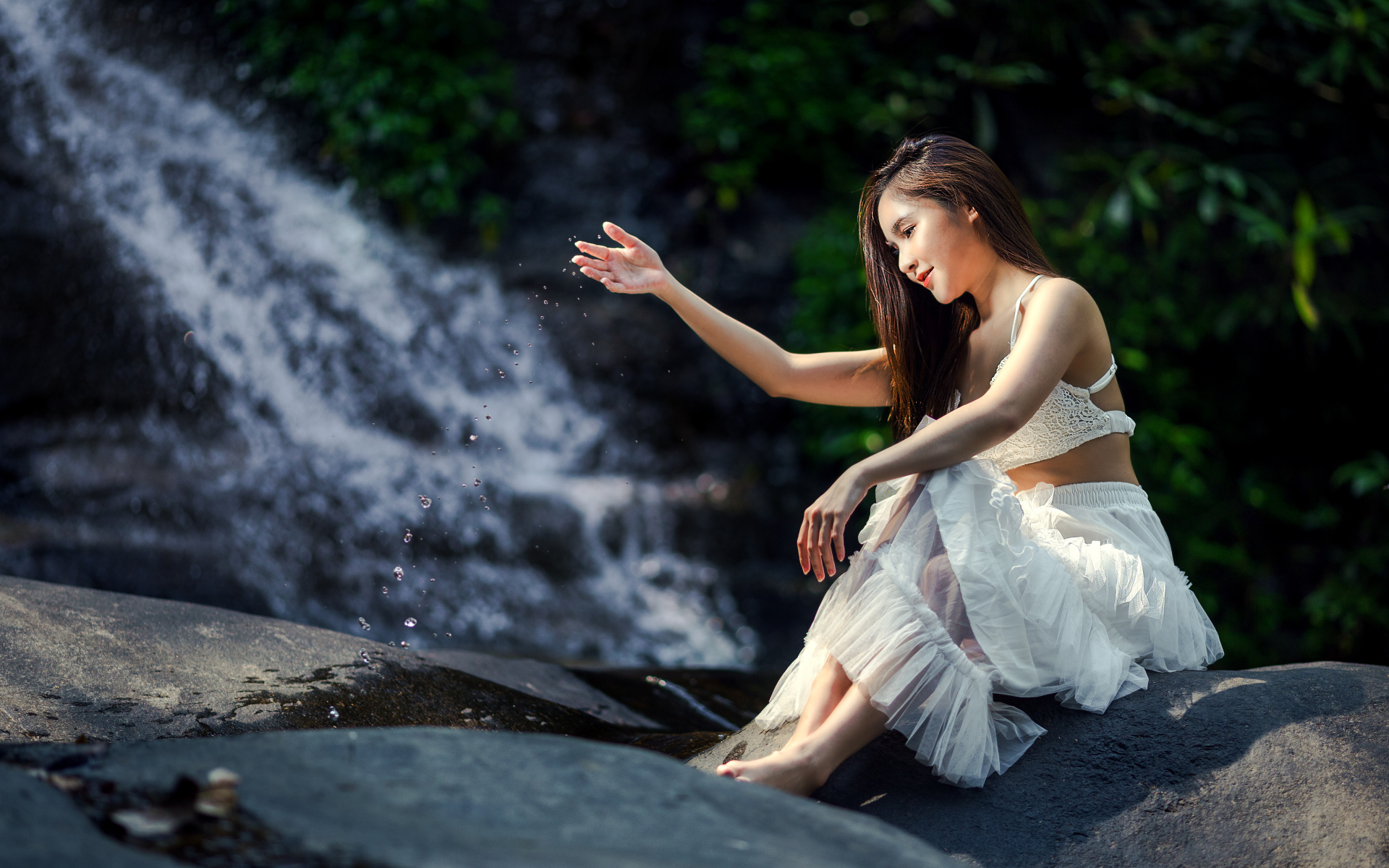 Красивая девушка азиатка в белом платье сидит у воды