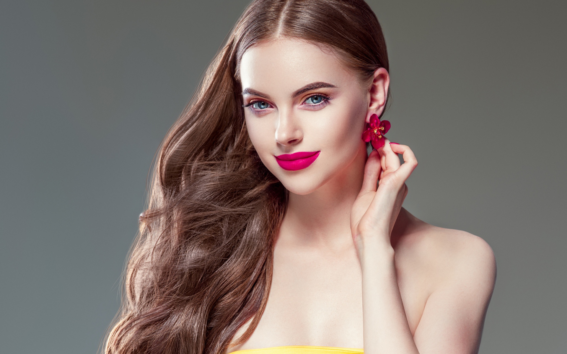 Красивая голубоглазая девушка с длинными волосами на сером фоне