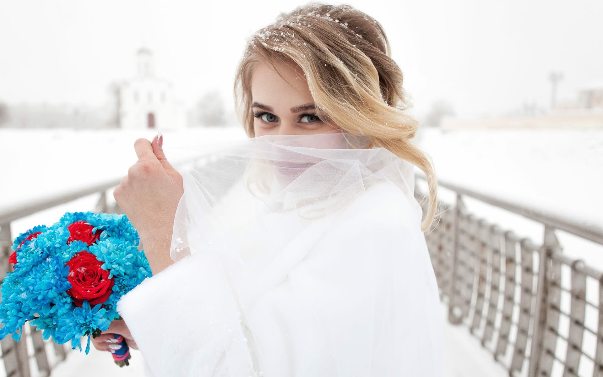 Красивая невеста с букетом в руках закрывает лицо фатой