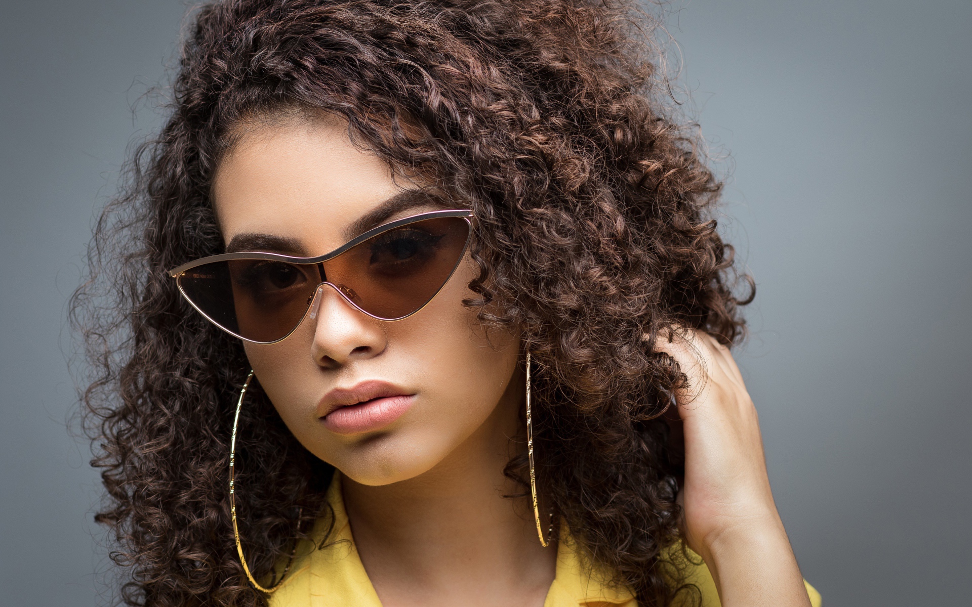 Красивая девушка в солнечных очках на сером фоне