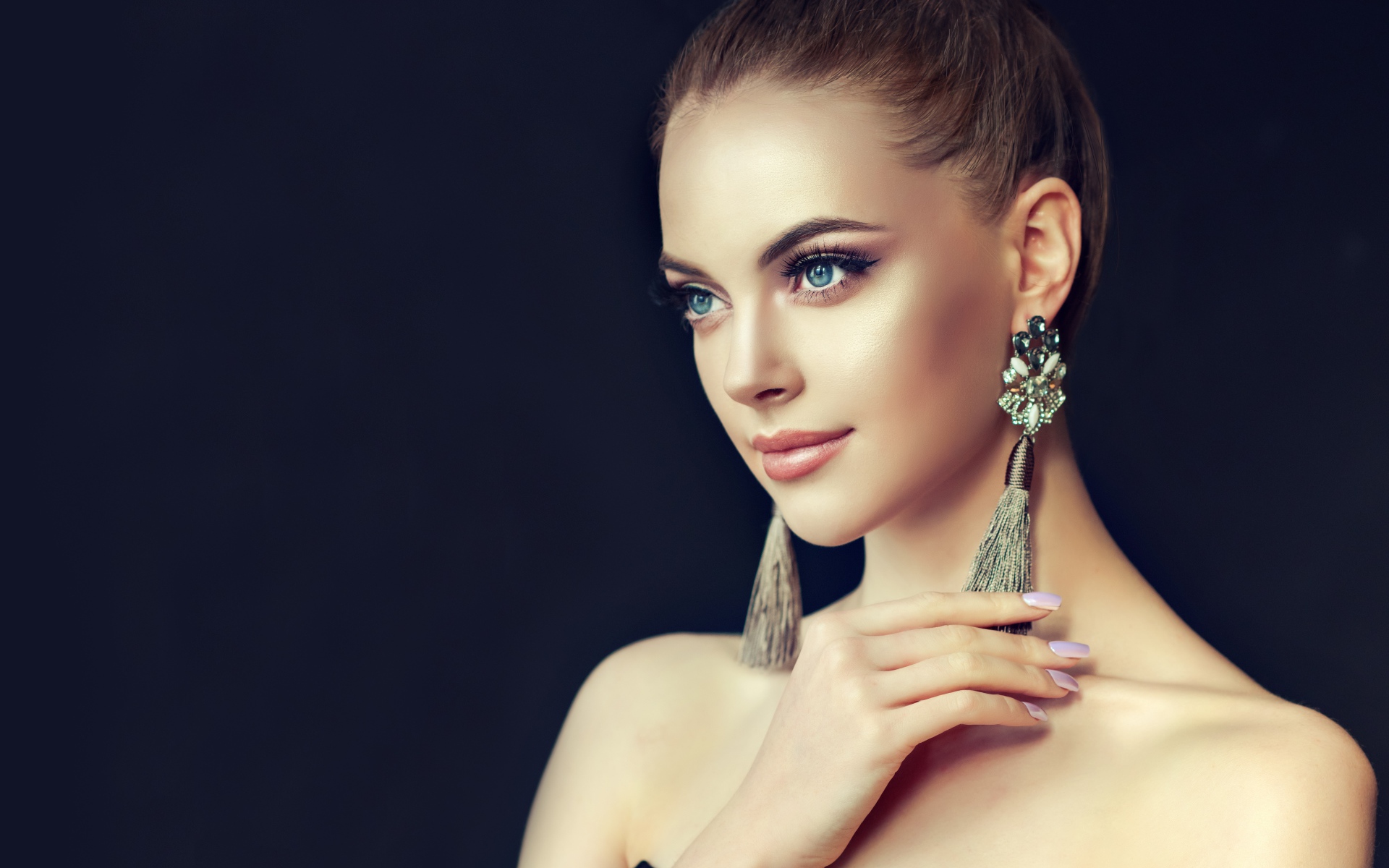 Красивая девушка с серьгами на черном фоне