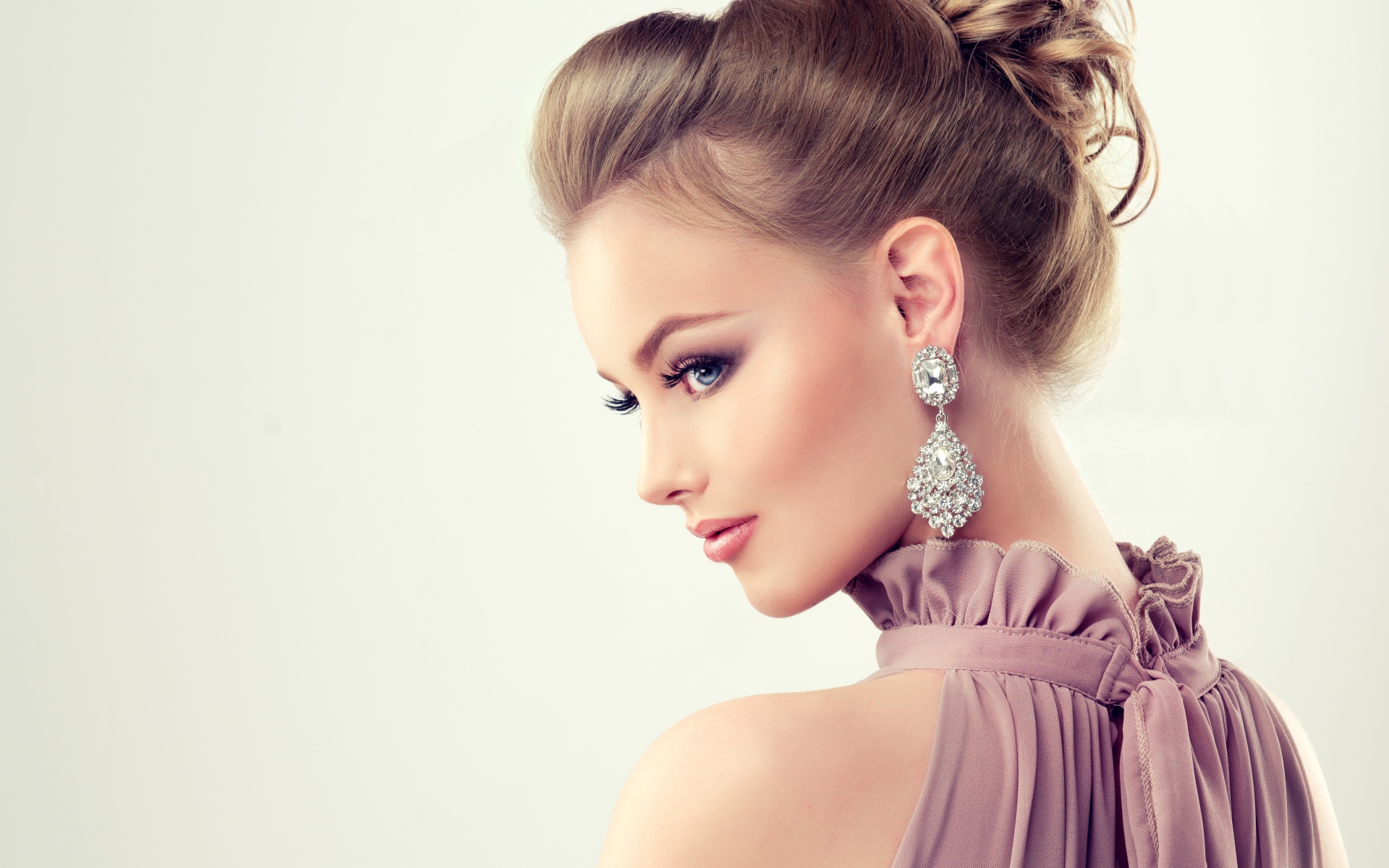 Красивая девушка с макияжем и прической на сером фоне