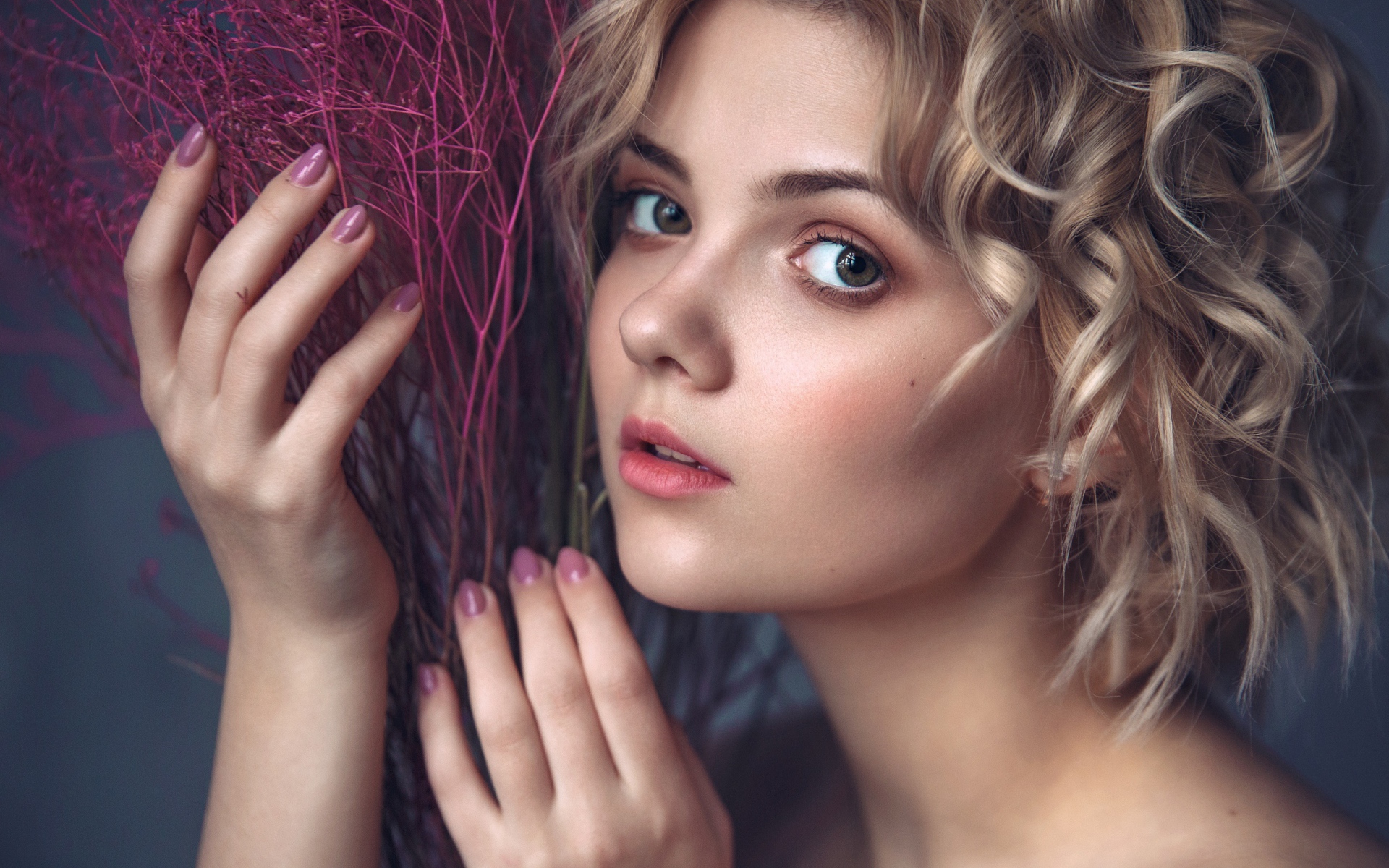 Красивая молодая блондинка с красным растением в руках