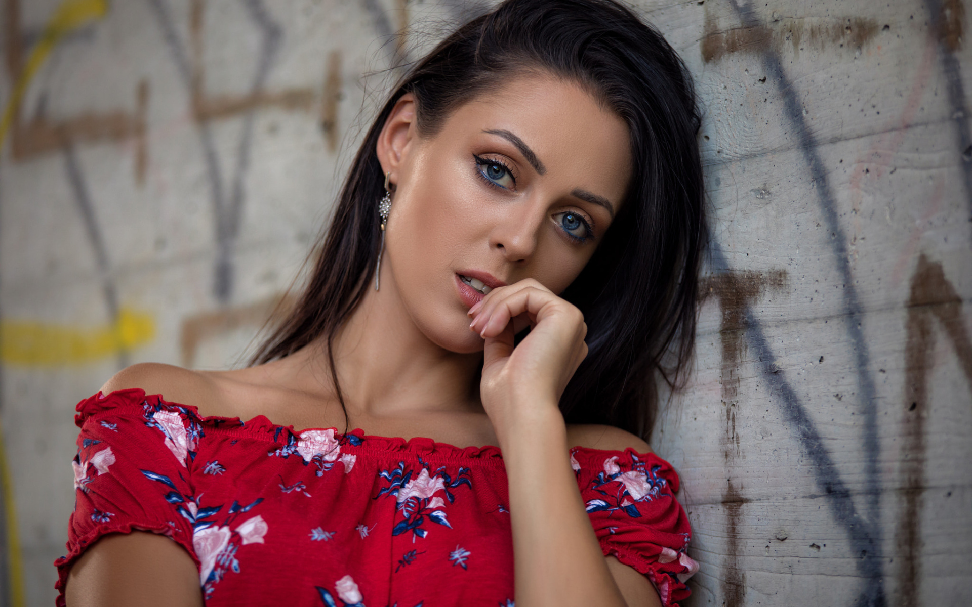 Голубоглазая брюнетка стоит в платье стоит стены