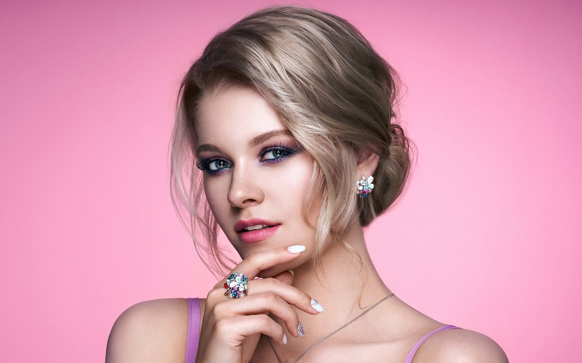 Стильная блондинка с прической на розовом фоне