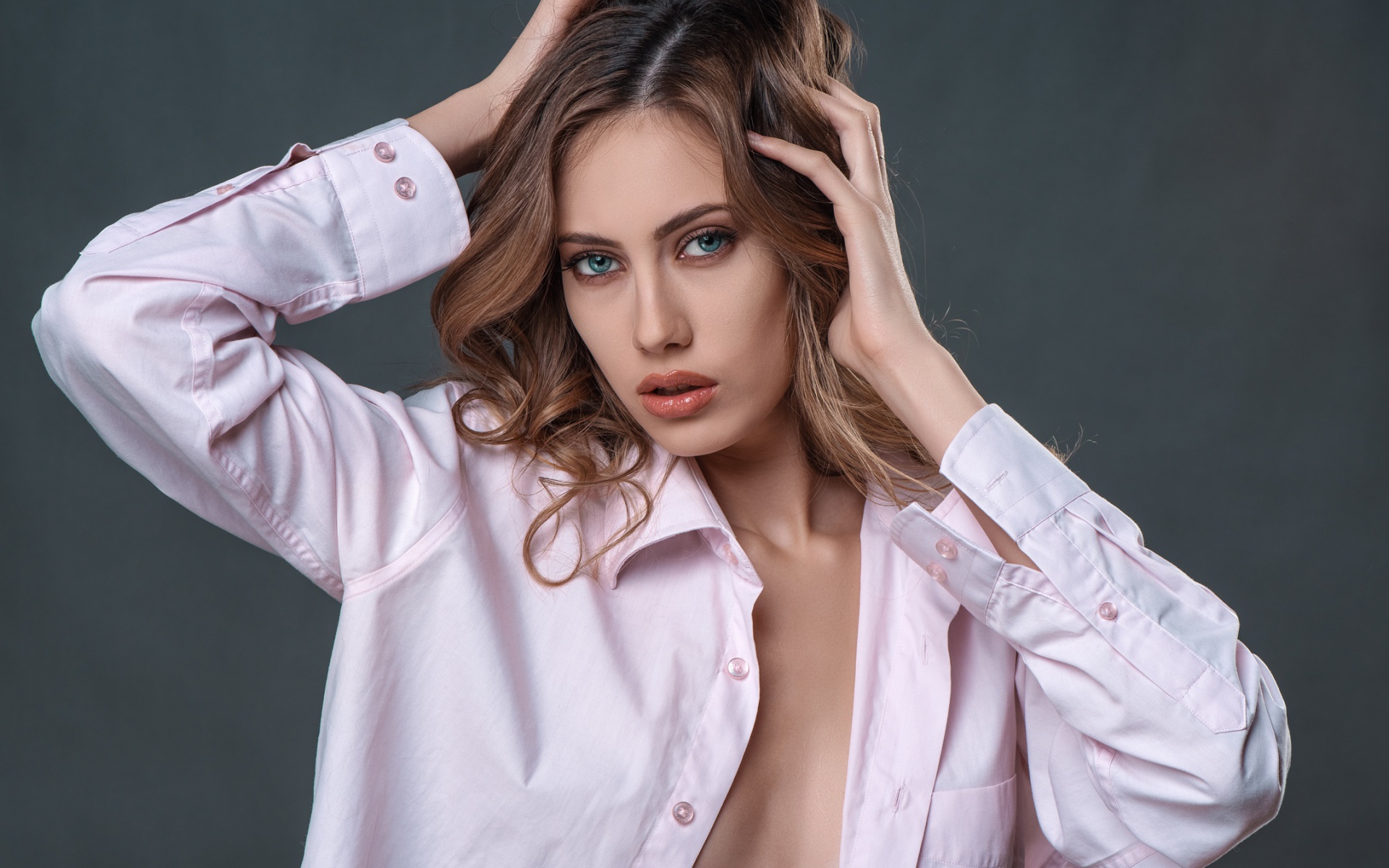 Стильная девушка в розовой рубашке на сером фоне