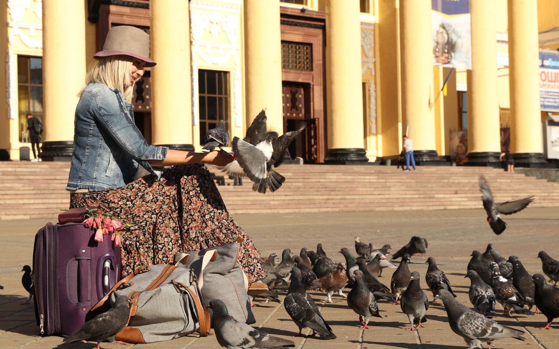 Молодая девушка кормит голубей на вокзале