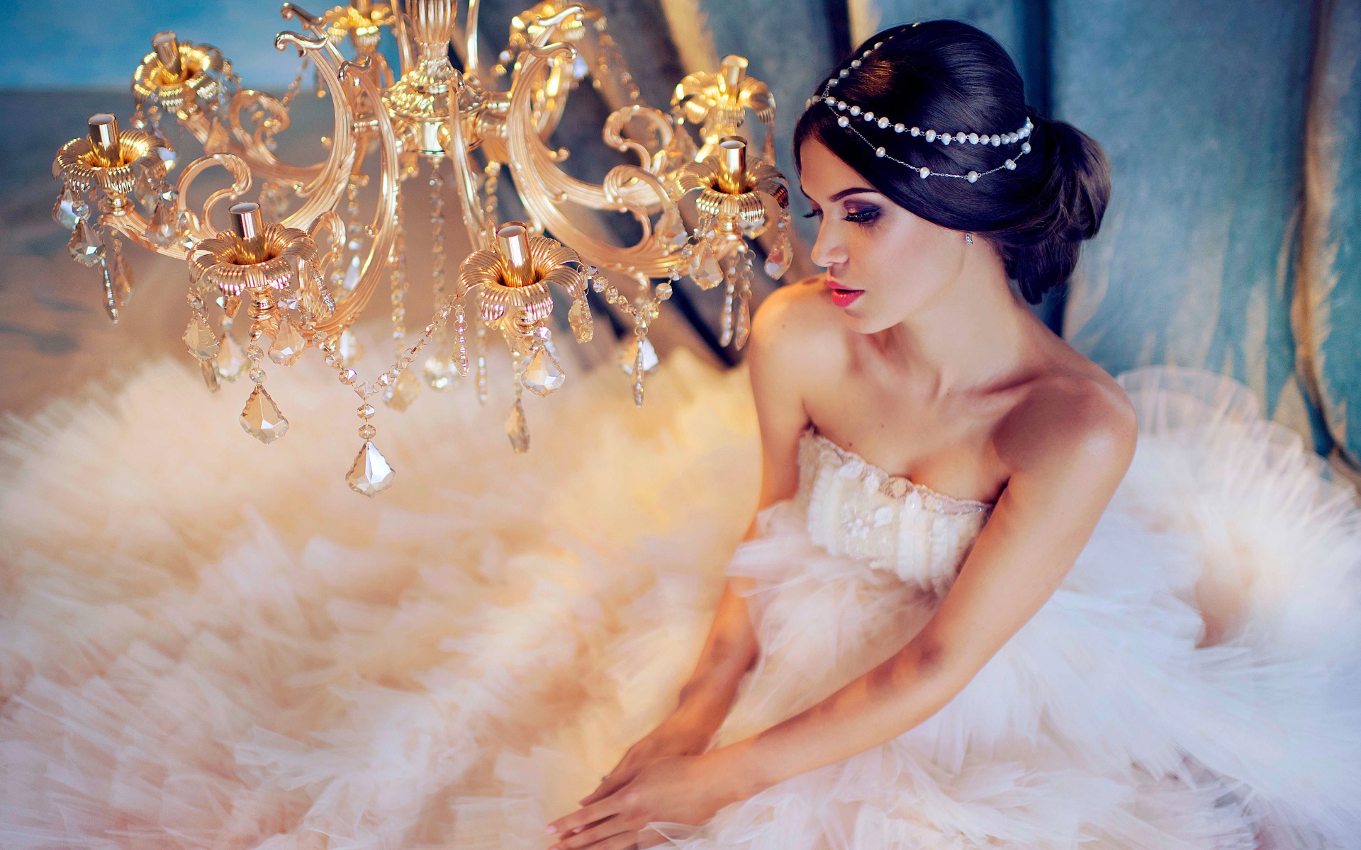 Молодая девушка в белом платье у красивой  люстры