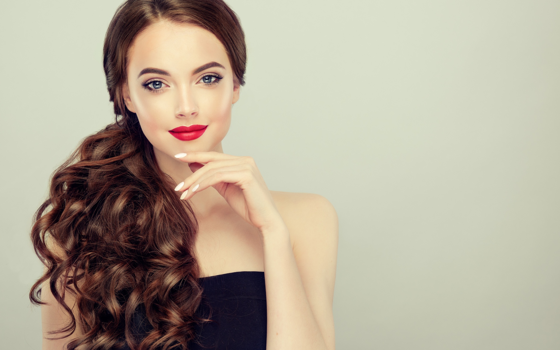 Молодая девушка с красивыми волосами на сером фоне