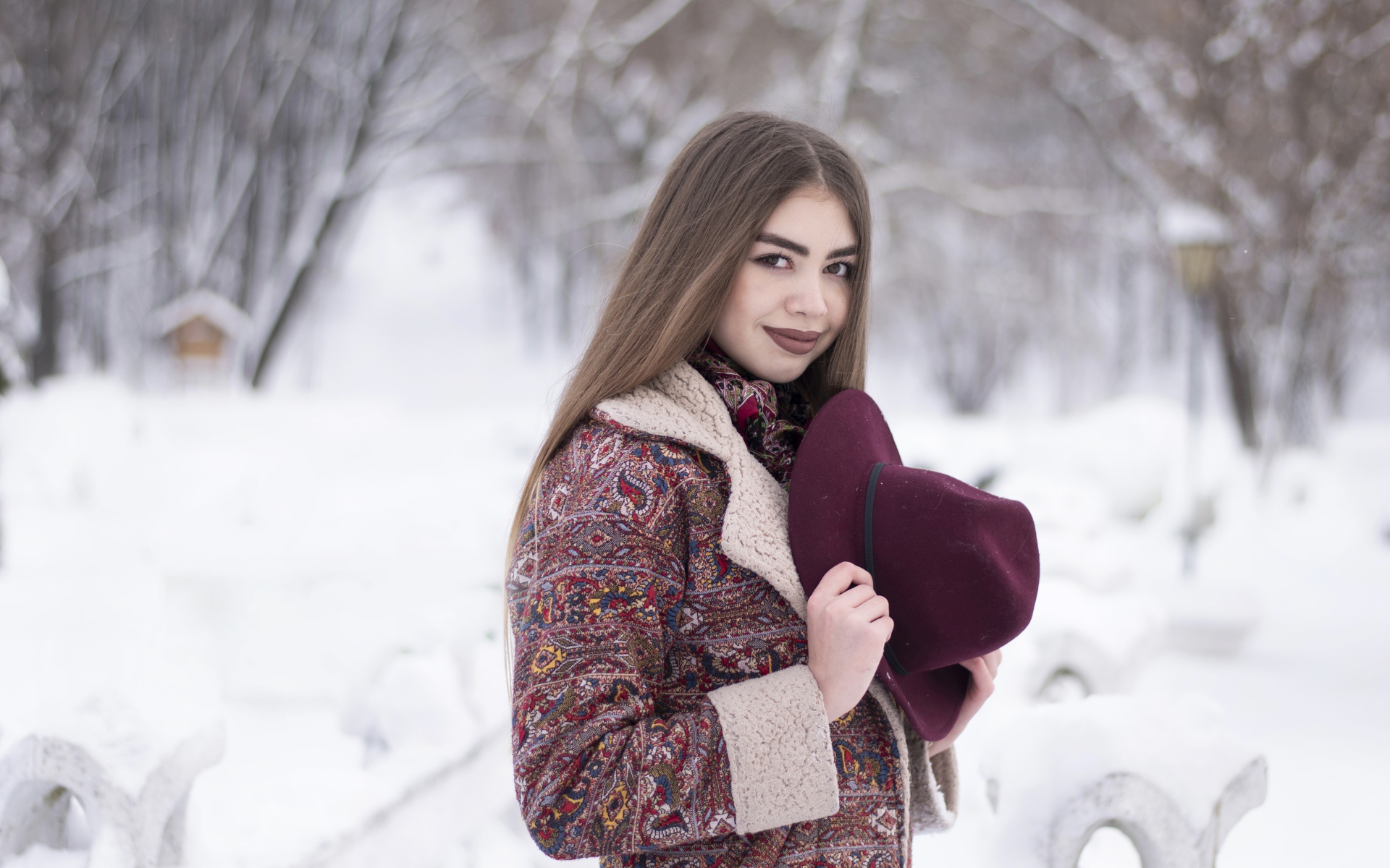 Молодая длинноволосая девушка шатенка с шляпой в руках зимой