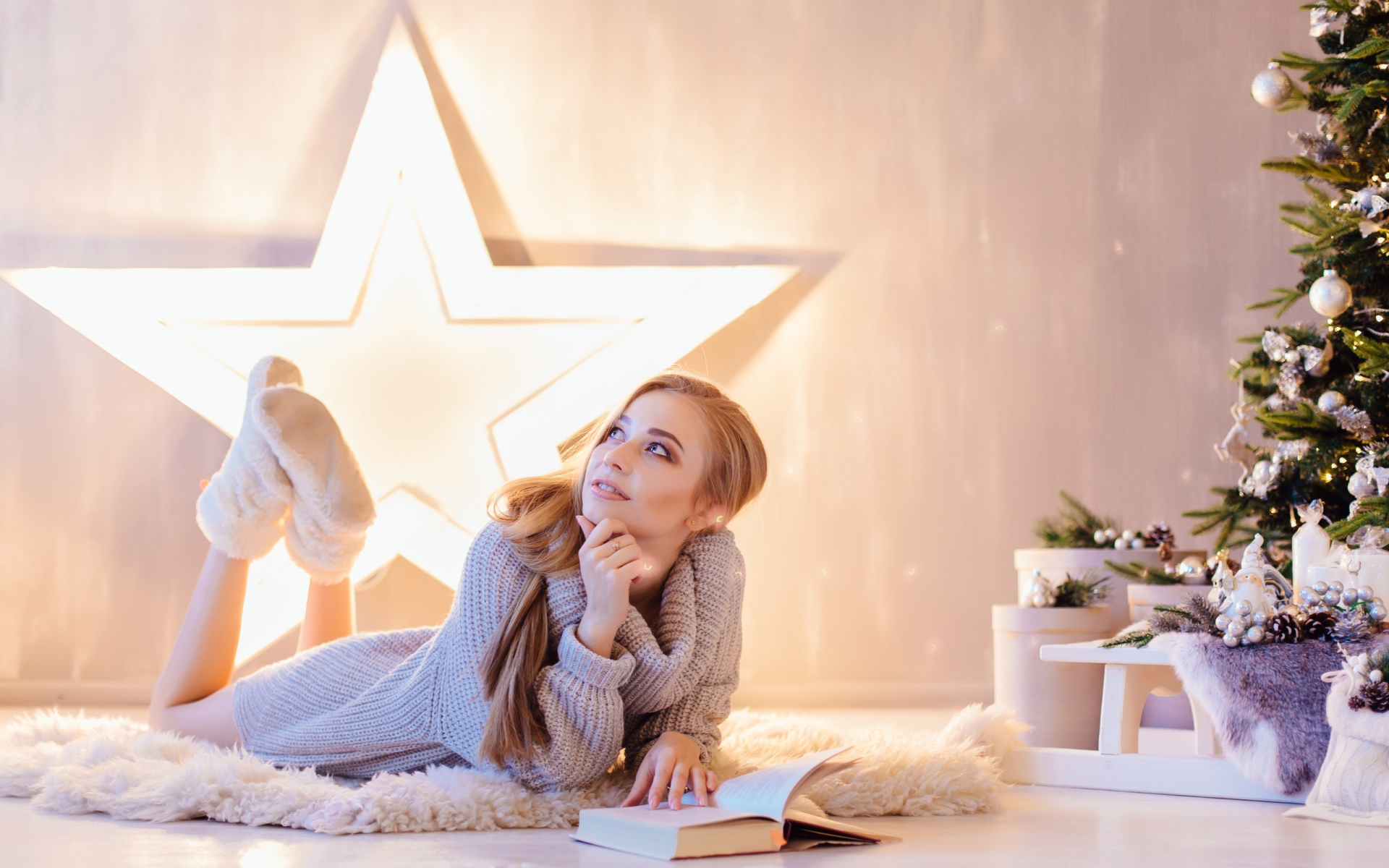 Красивая девушка читает книгу у новогодней елки