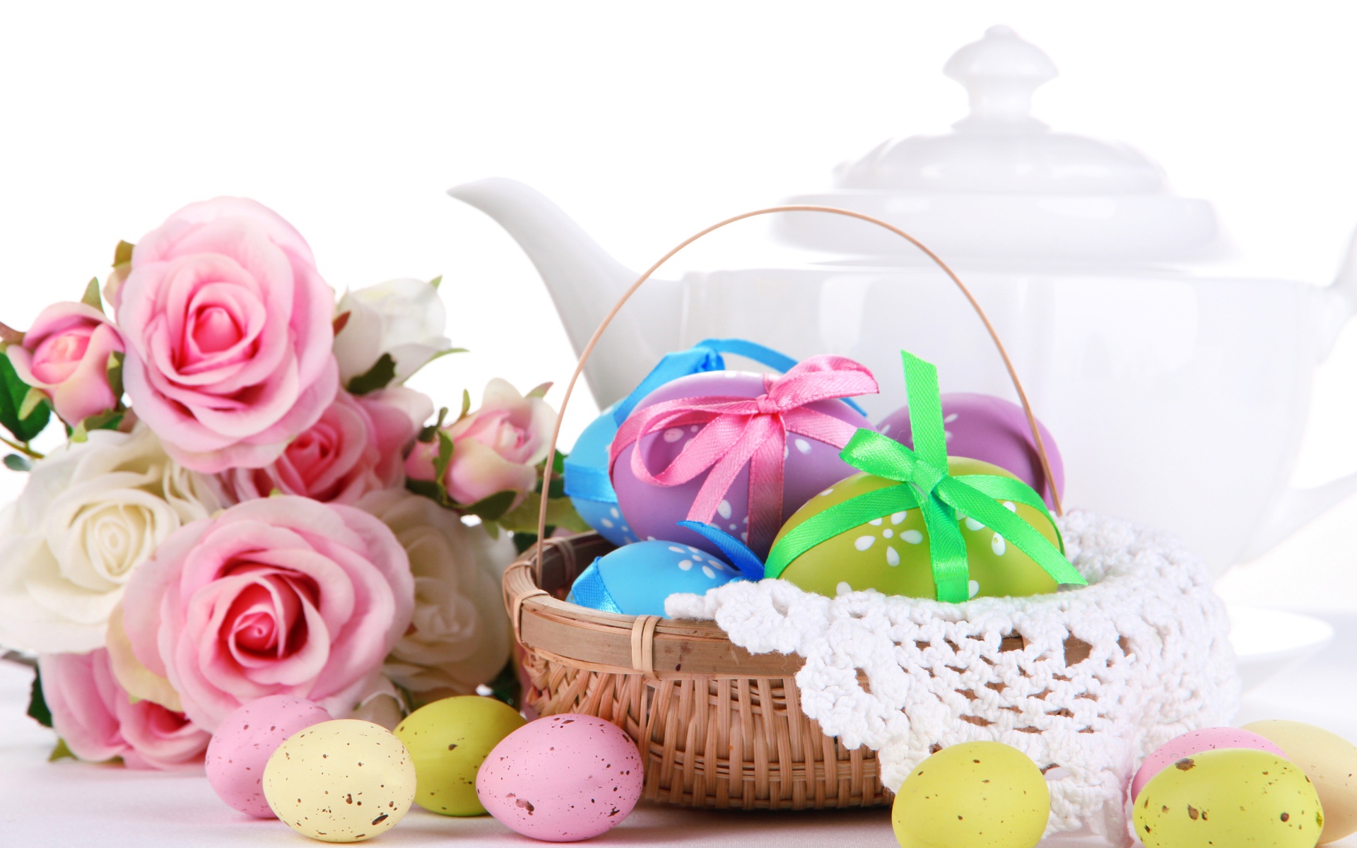 Корзина с пасхальными яйцами на столе с букетом роз и белым чайником