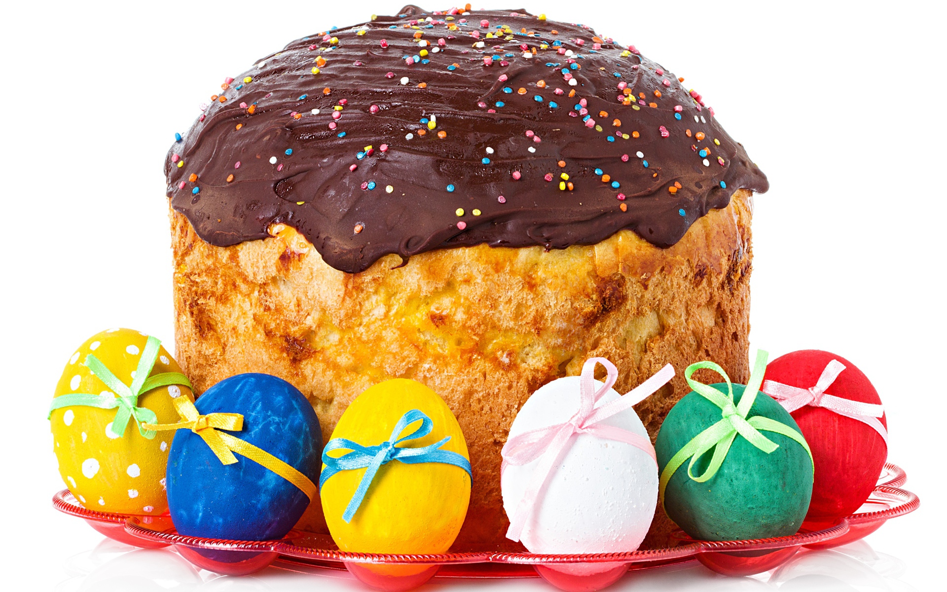 Большой пасхальный кулич с шоколадной глазурью на белом фоне с крашеными яйцами 