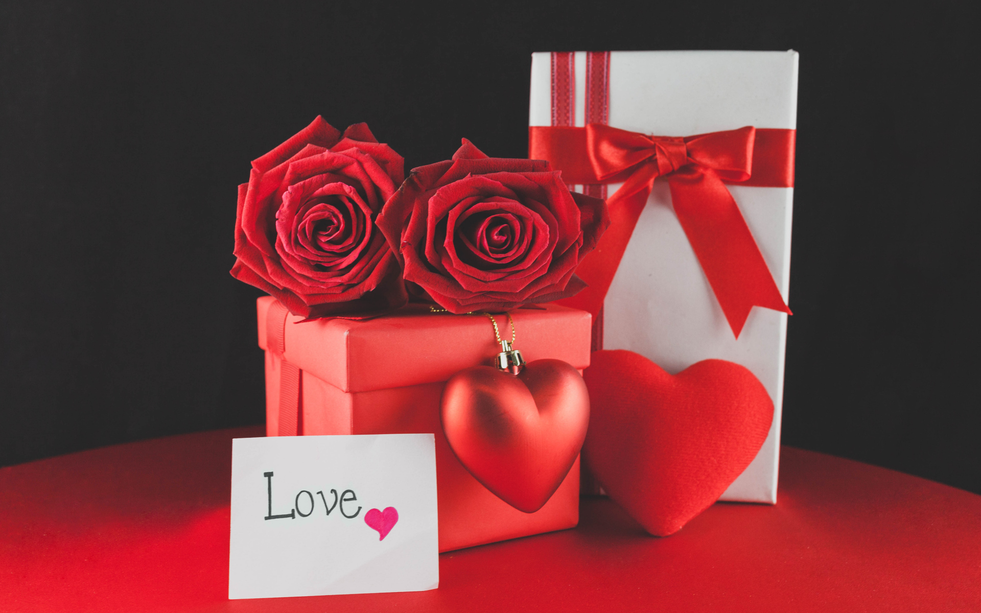 Коробки с подарками на столе с красными розами и сердцем