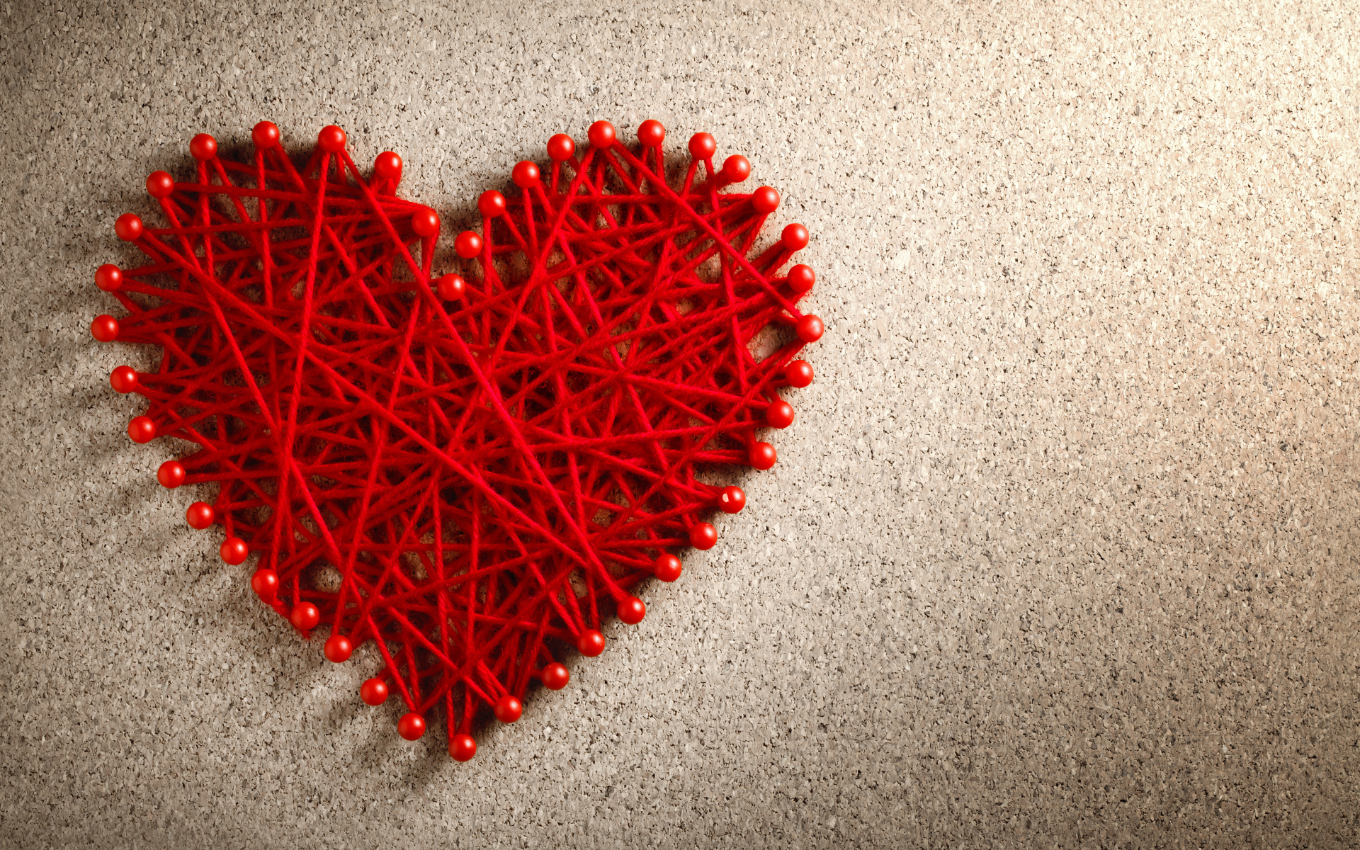 Сердце из красных нитей и невидимок на сером фоне