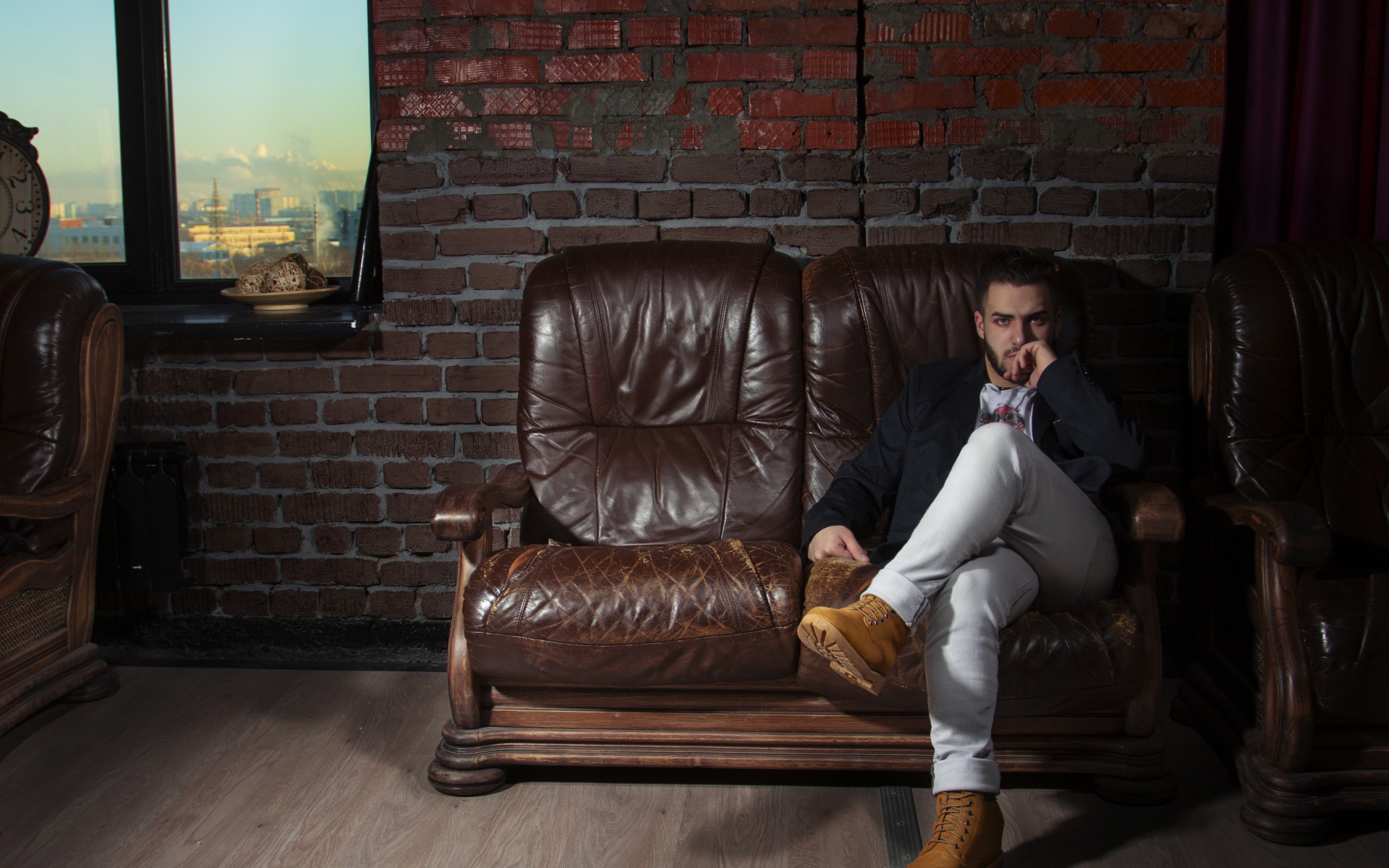 Стильный мужчина сидит в кожаном кресле 
