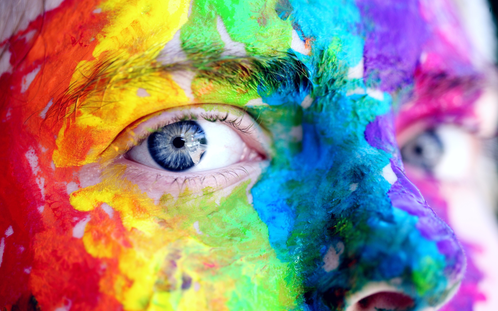 Лицо голубоглазого мужчины в разноцветных красках крупным планом