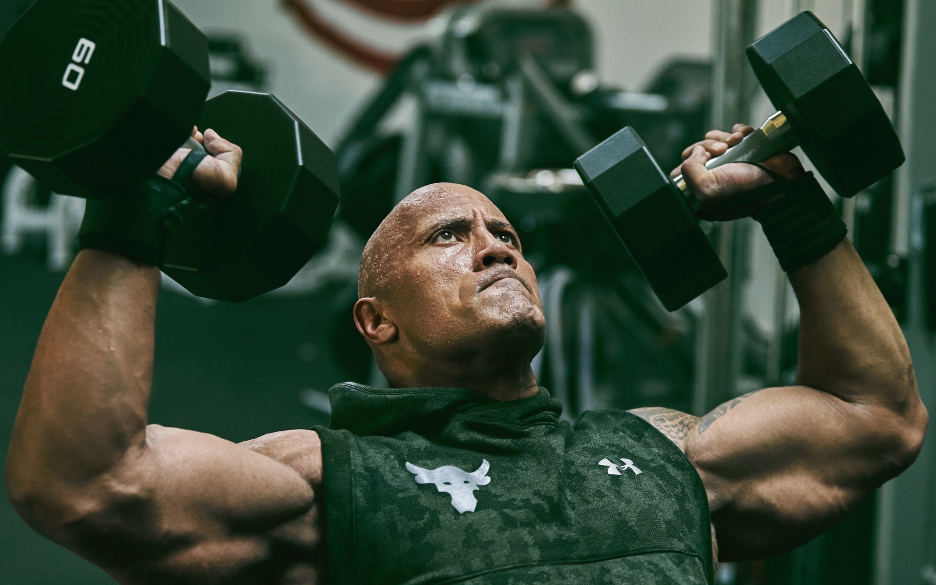 Американский актер, сильный мужчина Дуэйн Джонсон с гантелями в спортзале