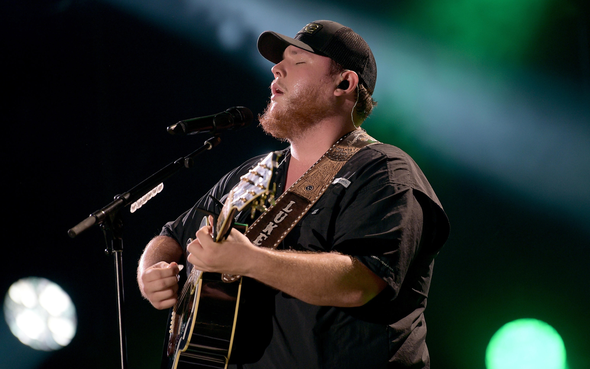 Кантри исполнитель Люк Комбс с гитарой поет на сцене