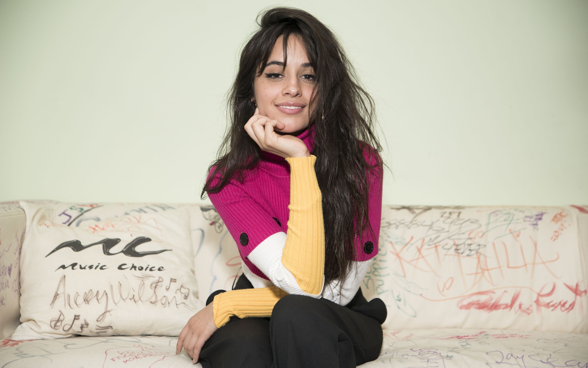 Улыбающаяся Камила Кабельо сидит на диване