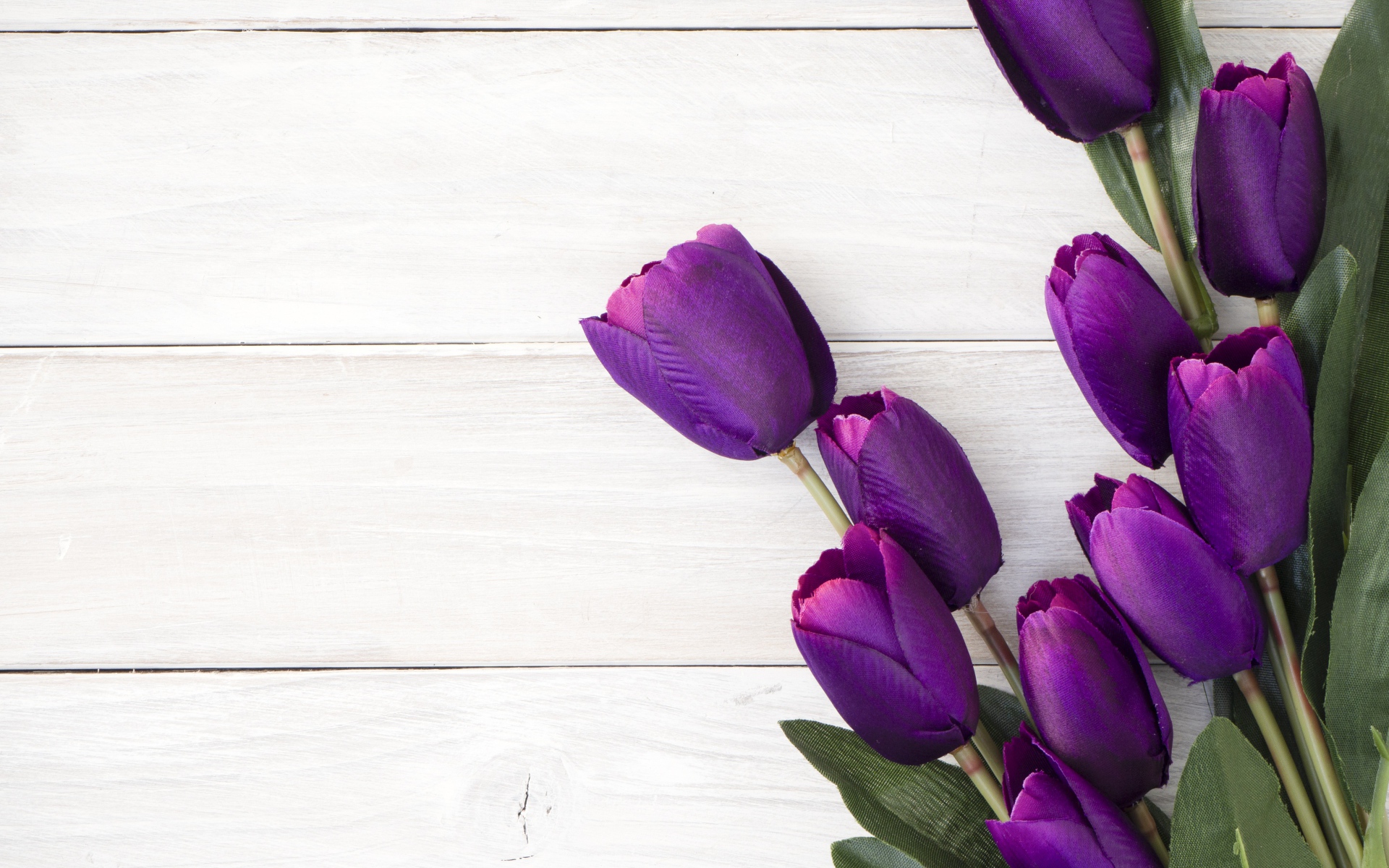 Букет искусственных фиолетовых тюльпанов на деревянном фоне