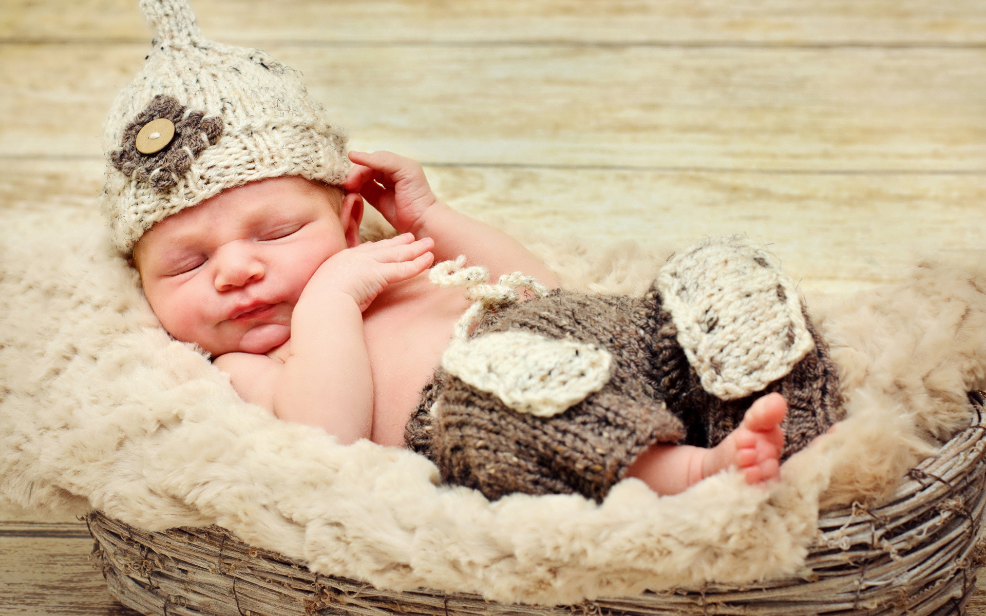 Маленький мальчик в вязаной шапке спит в корзине