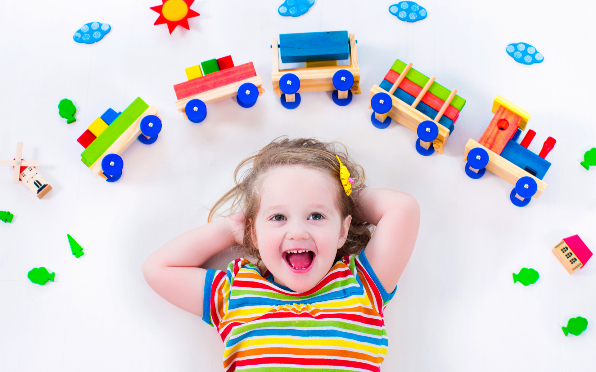 Маленькая девочка на сером фоне с игрушечным паровозом 