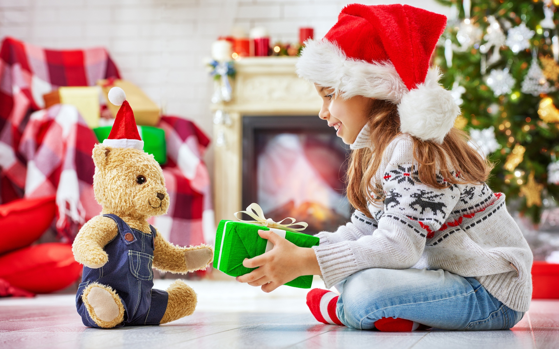 Маленькая девочка с медвежонком Тедди у елки с подарками на Новый год