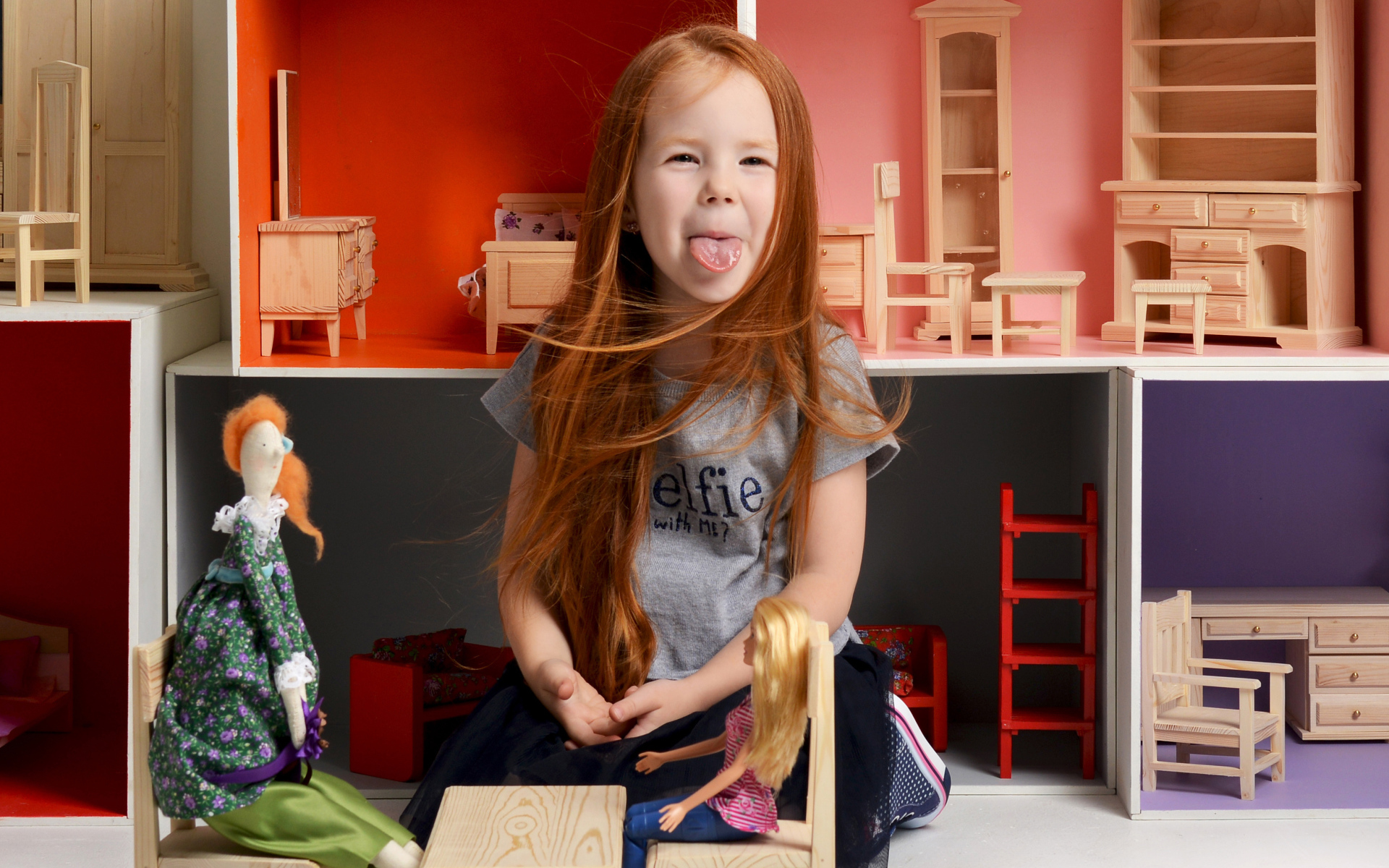 Маленькая длинноволосая девочка показывает язык