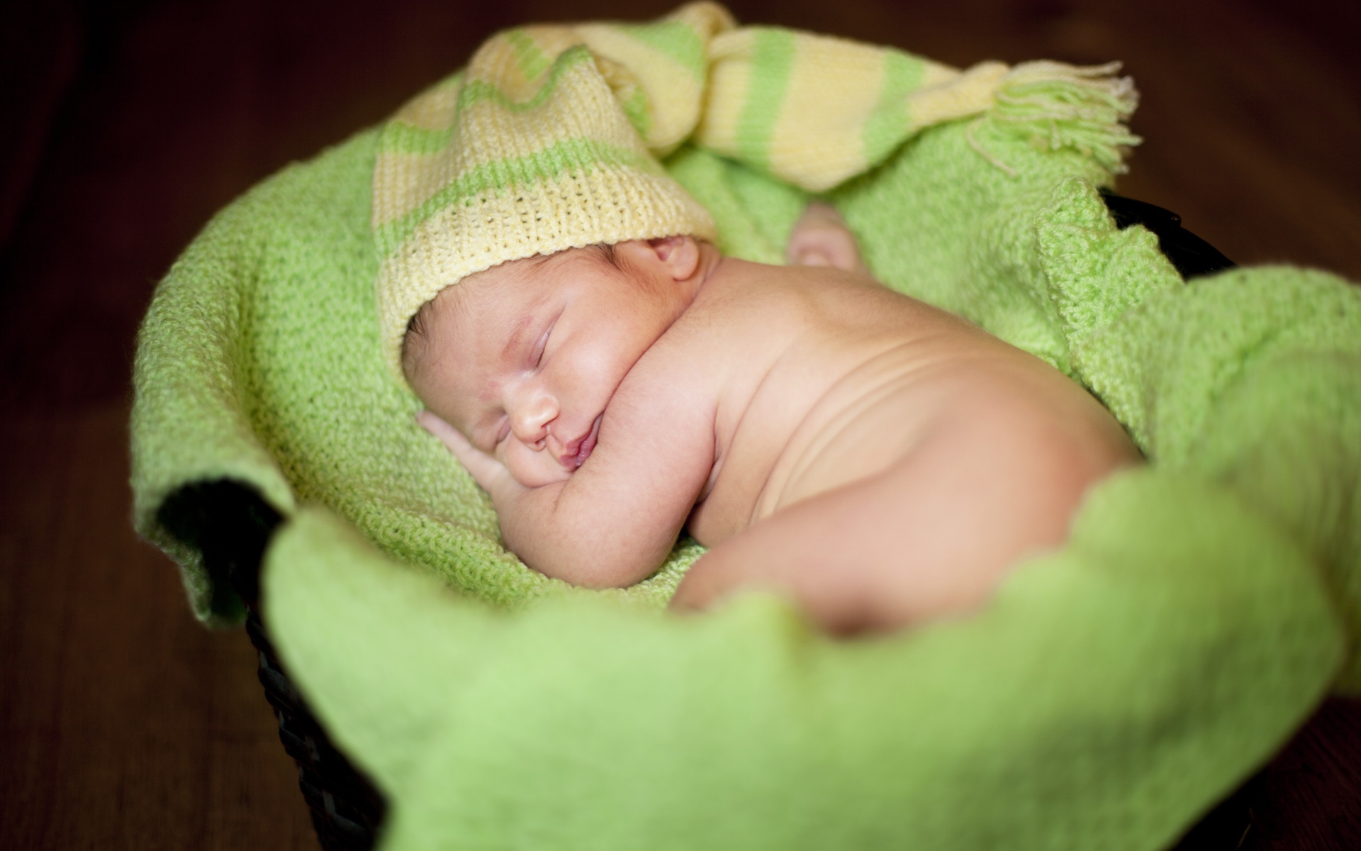 Маленький спящий грудной ребенок на зеленом покрывале 