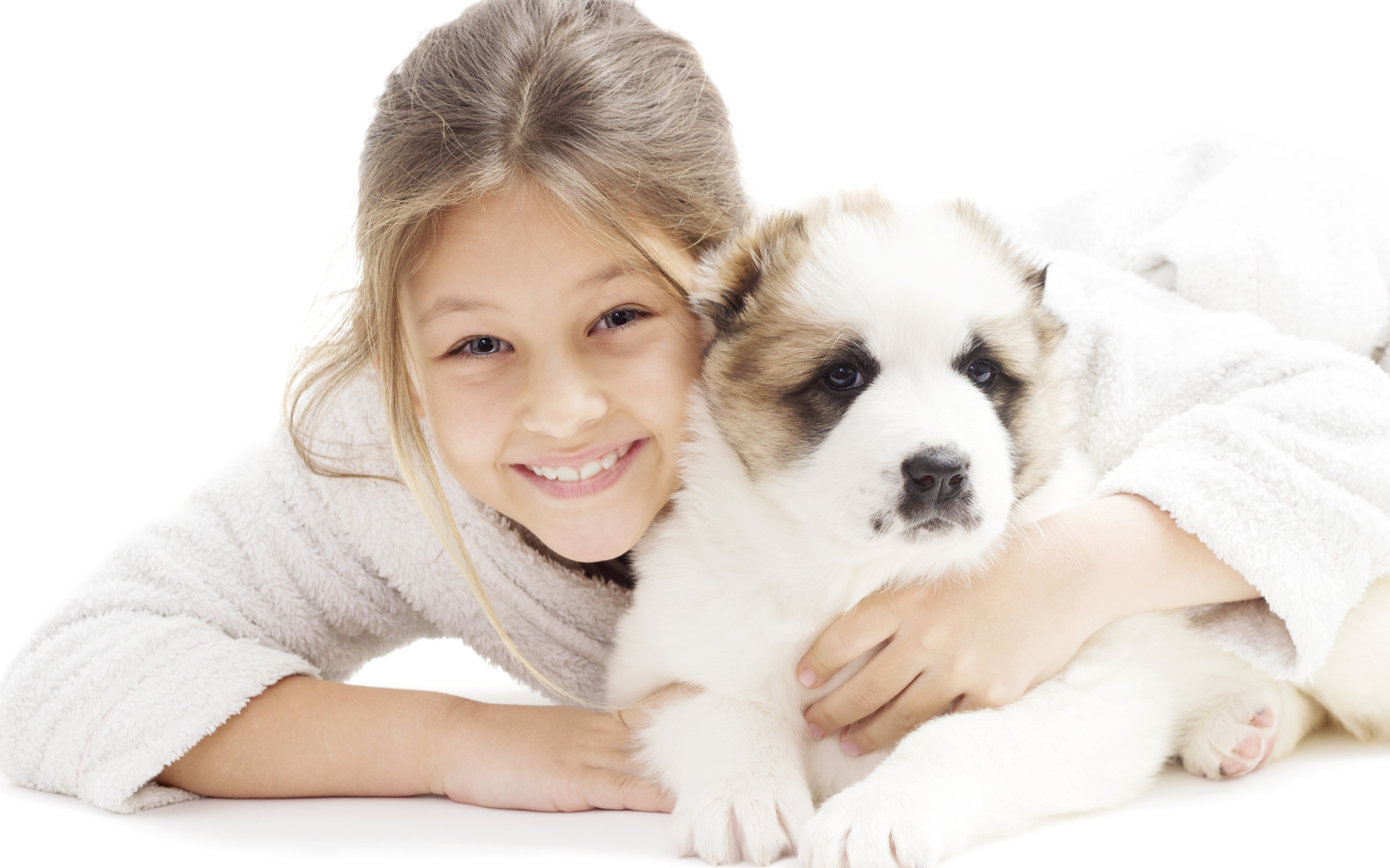 Улыбающаяся девочка лежит с щенком алабая