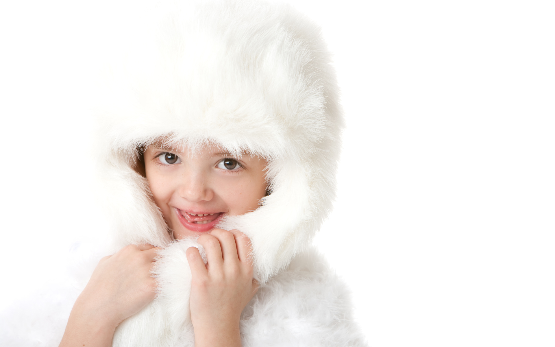 Улыбающаяся маленькая девочка в белой меховой шапке