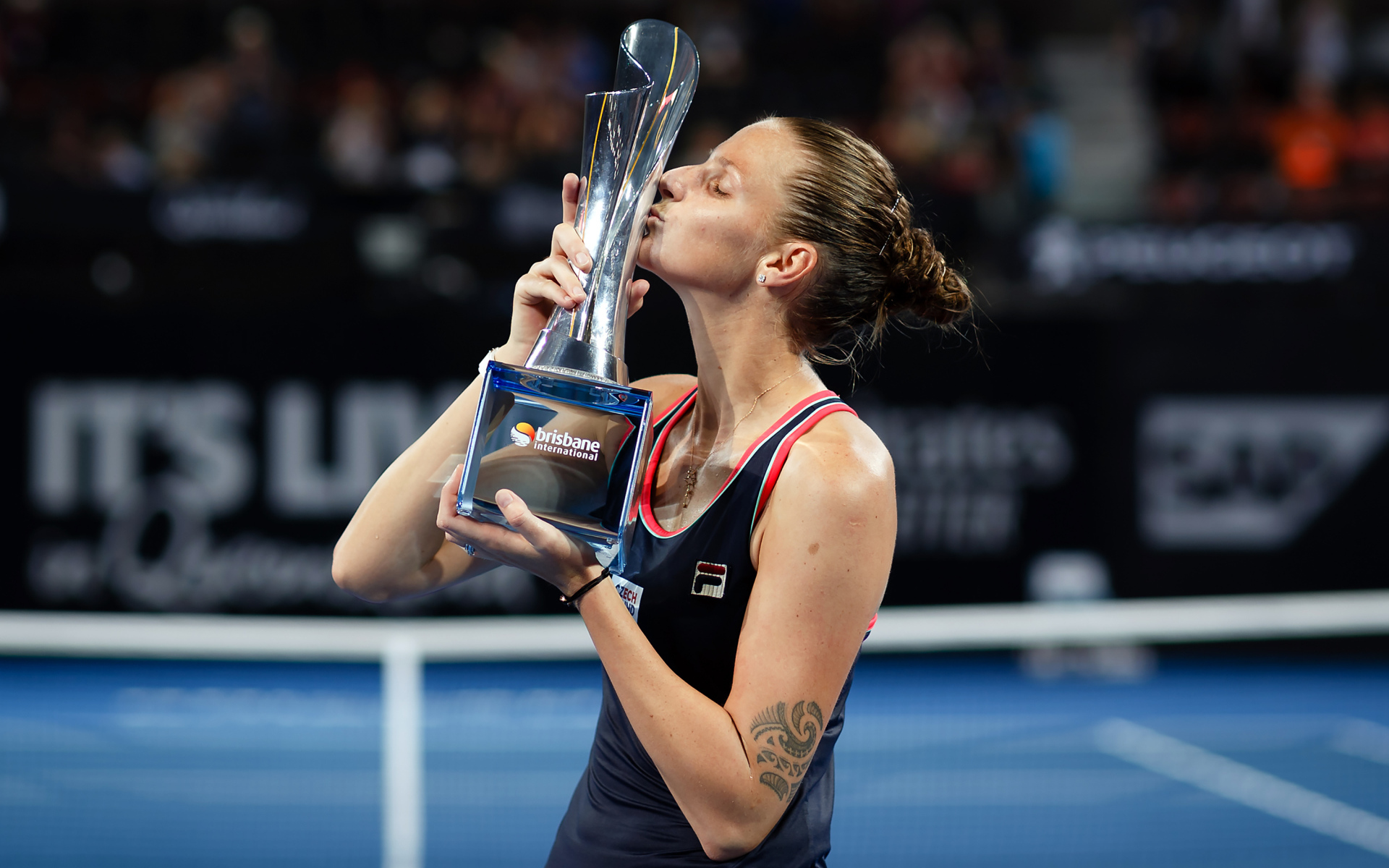 Чешская теннисистка Каролина Плишкова целует кубок на корте