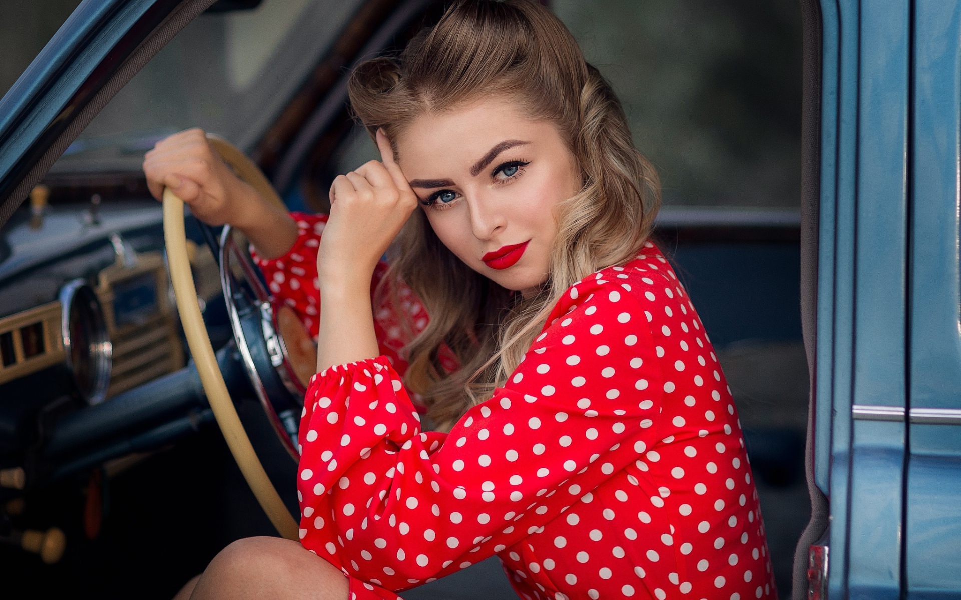 Голубоглазая ретро девушка за рулем автомобиля 