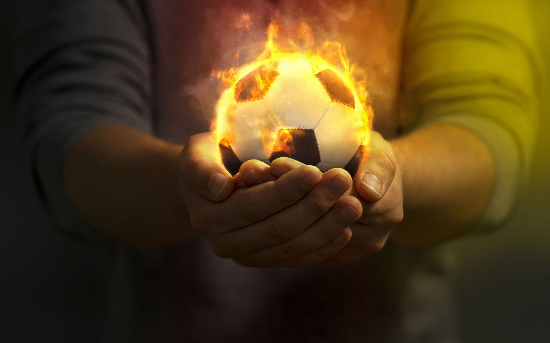 Огненный футбольный мяч в руках 