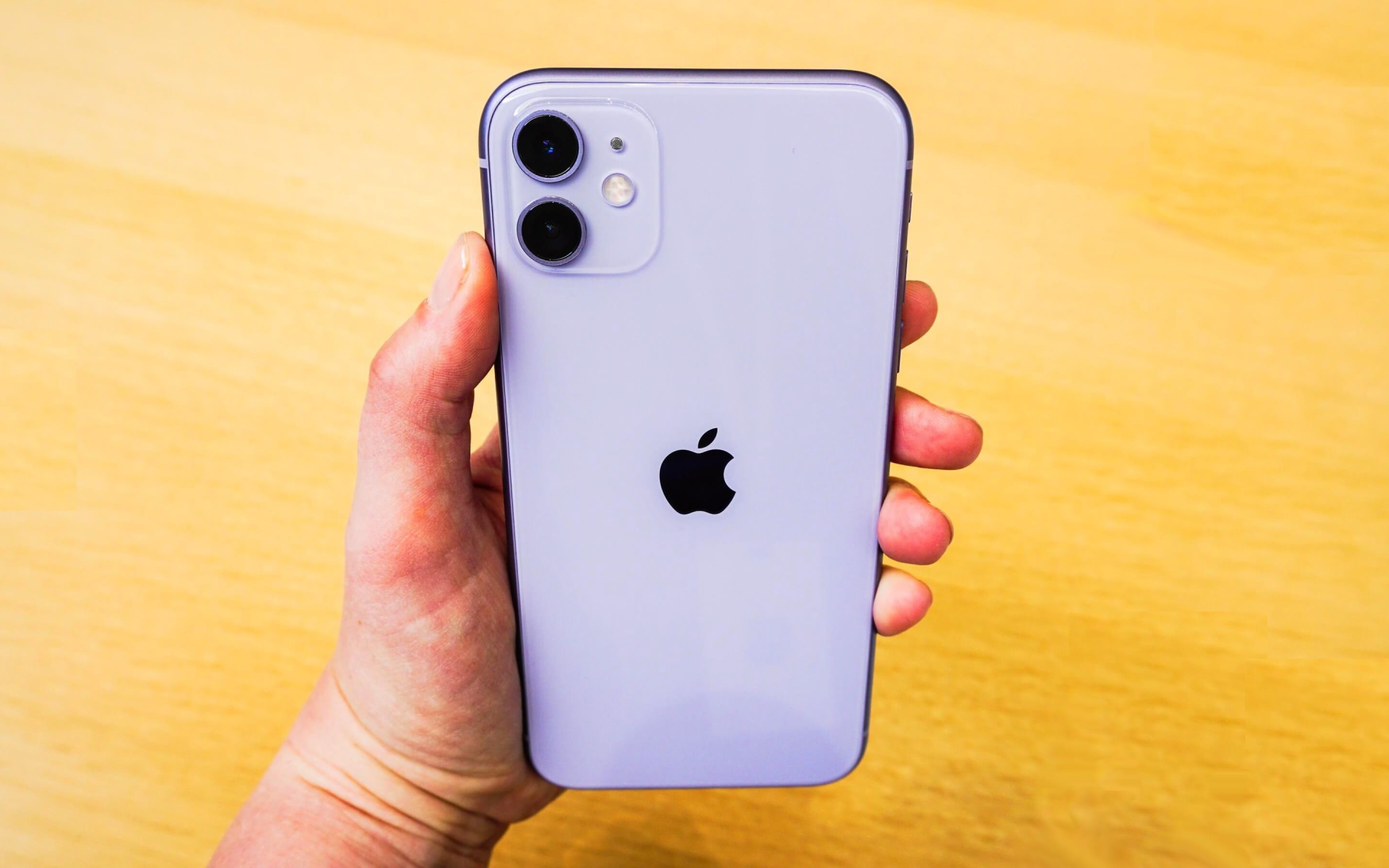 Новый Iphone 11 Pro Max в руке на желтом фоне