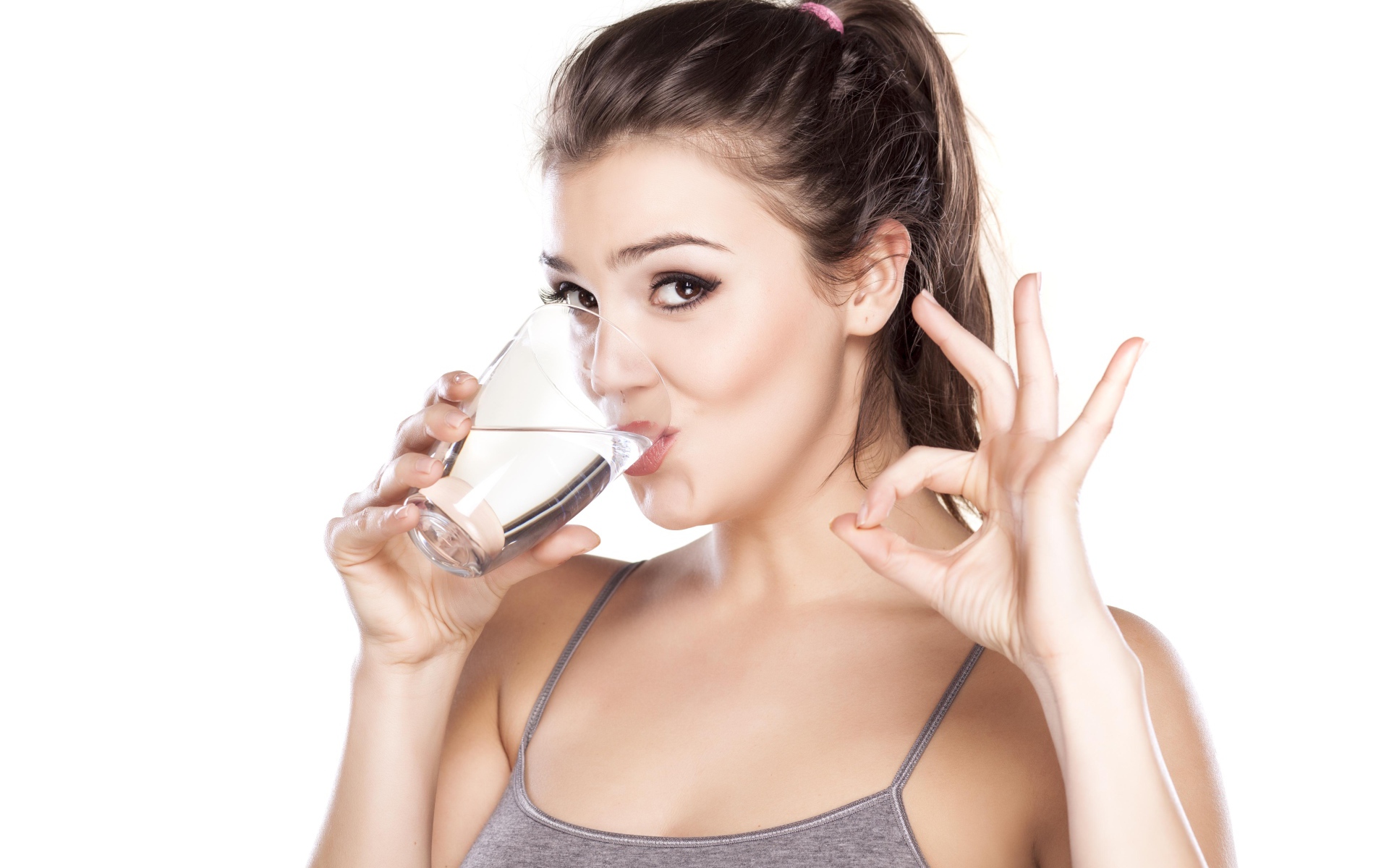 Young athletic girl drinks water from a glass