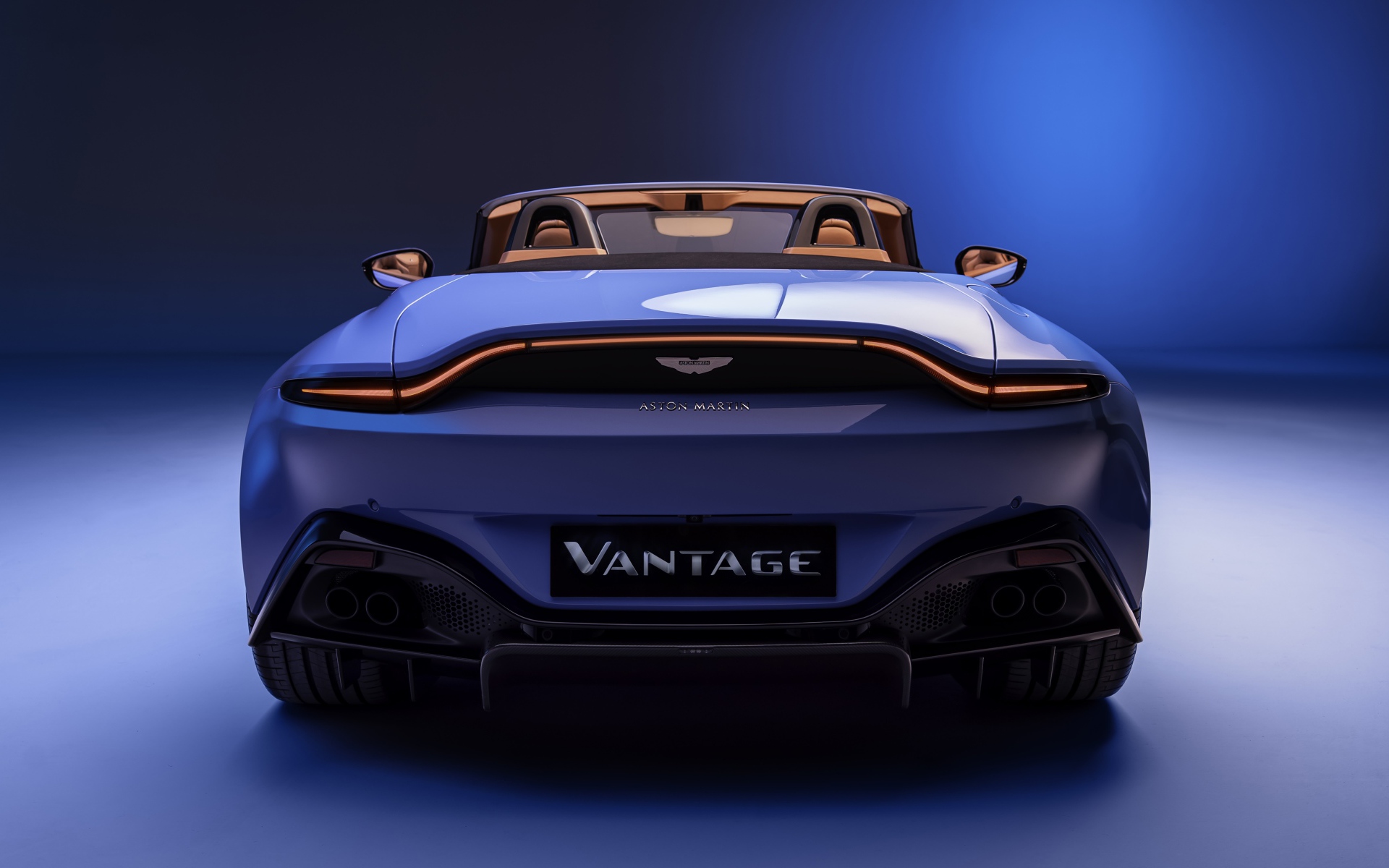 Голубой автомобиль Aston Martin Vantage Roadster 2020 года вид сзади