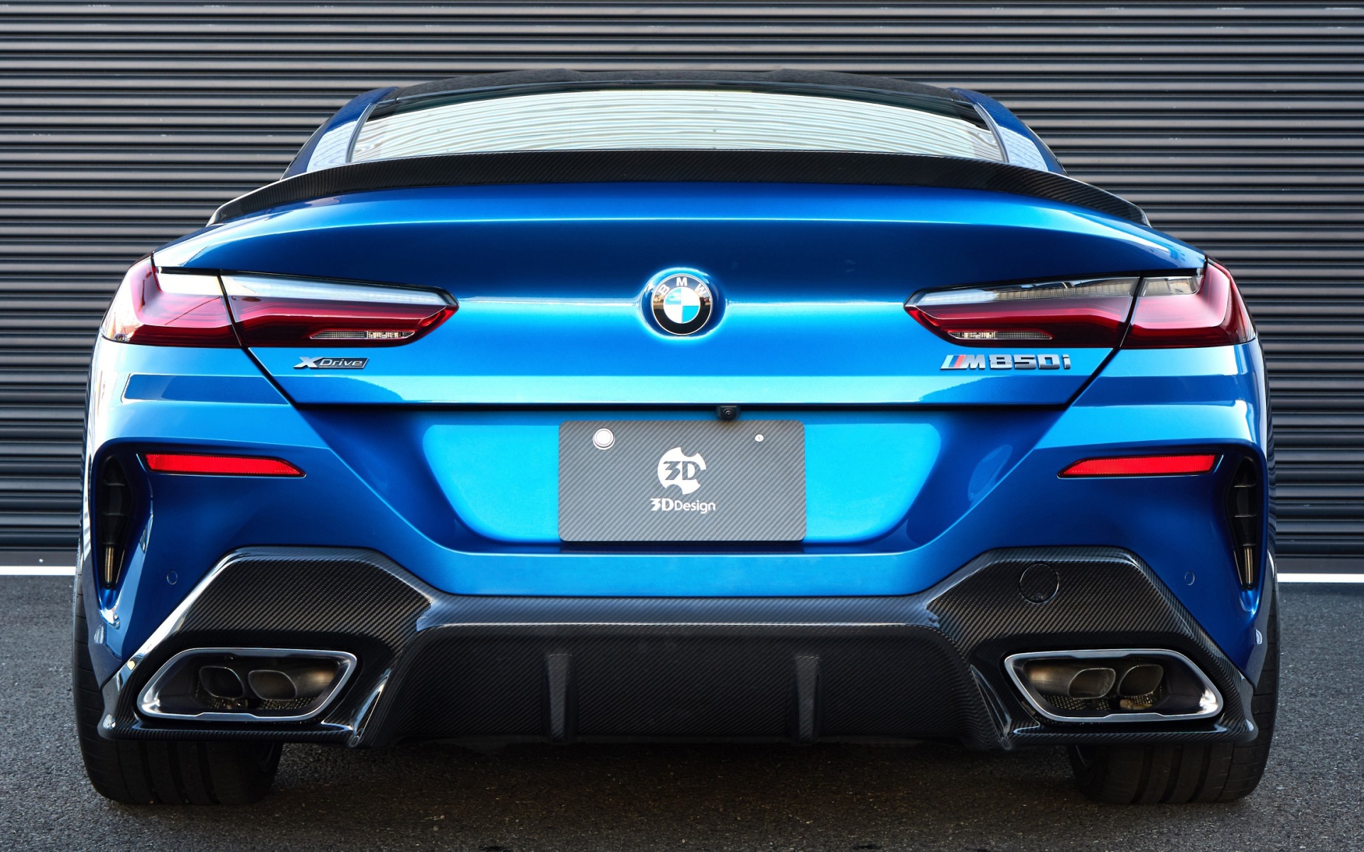 Синий автомобиль BMW M850i XDrive Coupe 2020 года вид сзади